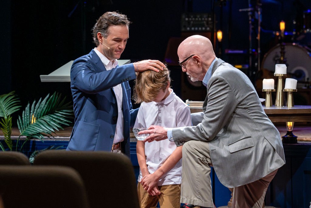 Pastors John Bourgeois and Jack Foster baptizing a child on Sunday morning