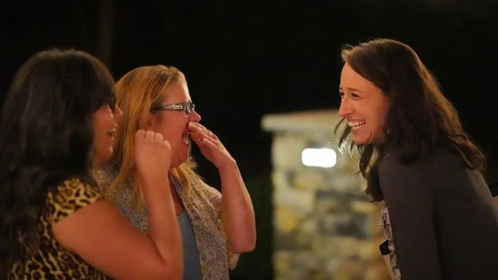 Three women enjoying a laugh together outdoor at a West End Womens event.