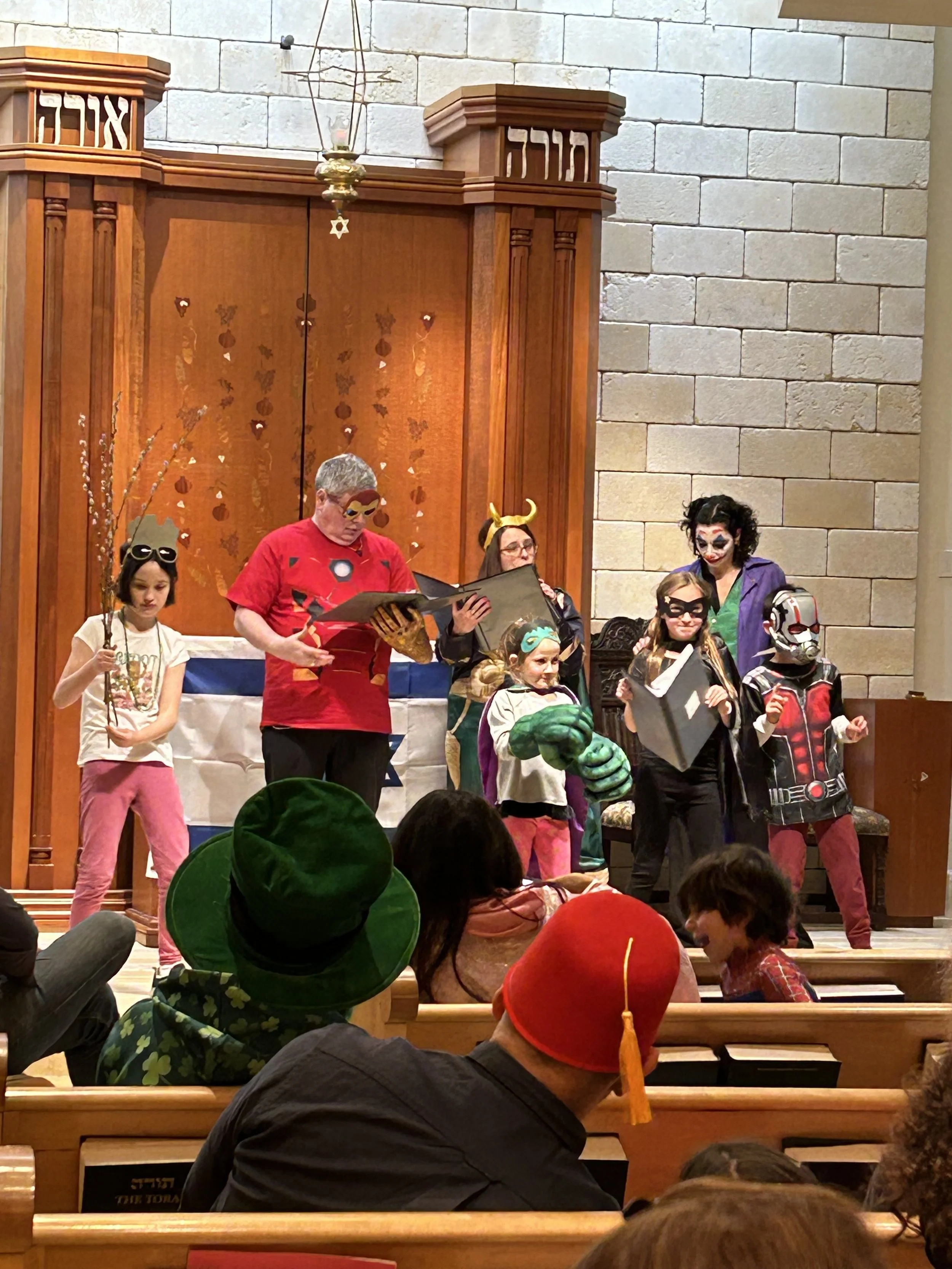 associate rabbi bailey romano and cantor ayelet porzecanski lead the purim spiel adults and children from the synagogue, all dressed as marvel heroes and villains