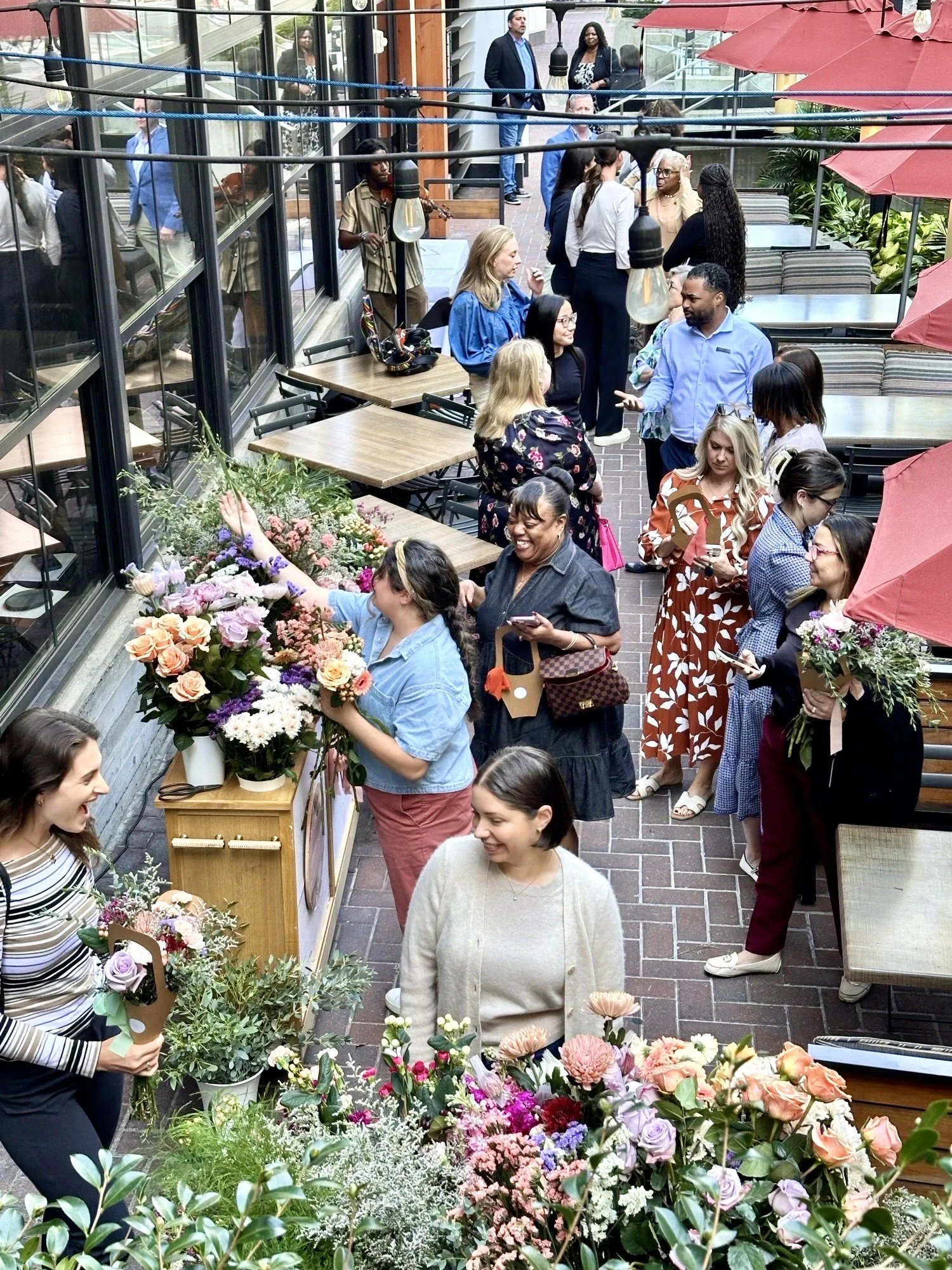 Women building bouquets at a flower bar cart outside on a restaurant patio