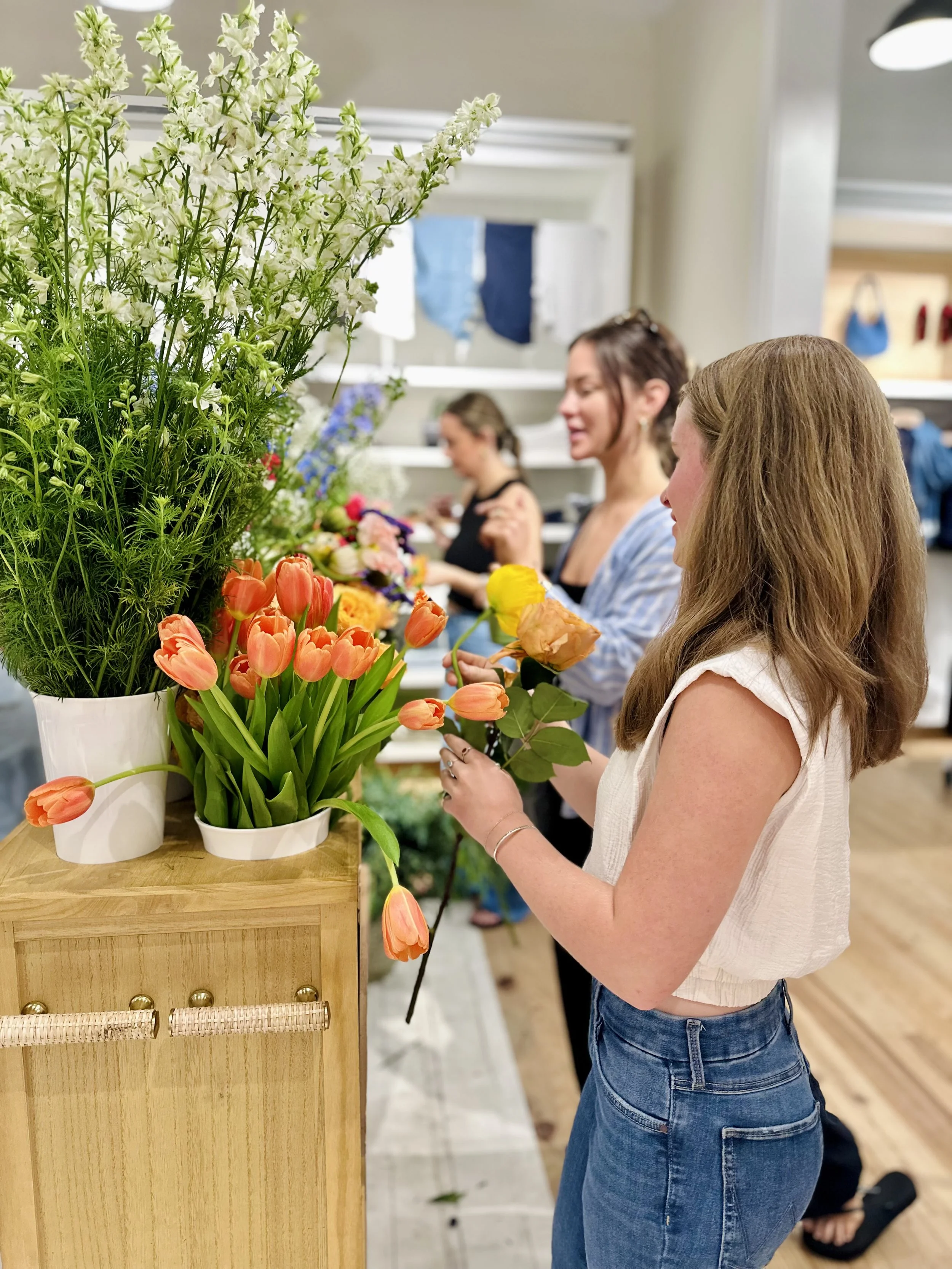 Women’s pulling flowers from vases on a flower cart in a clothing store