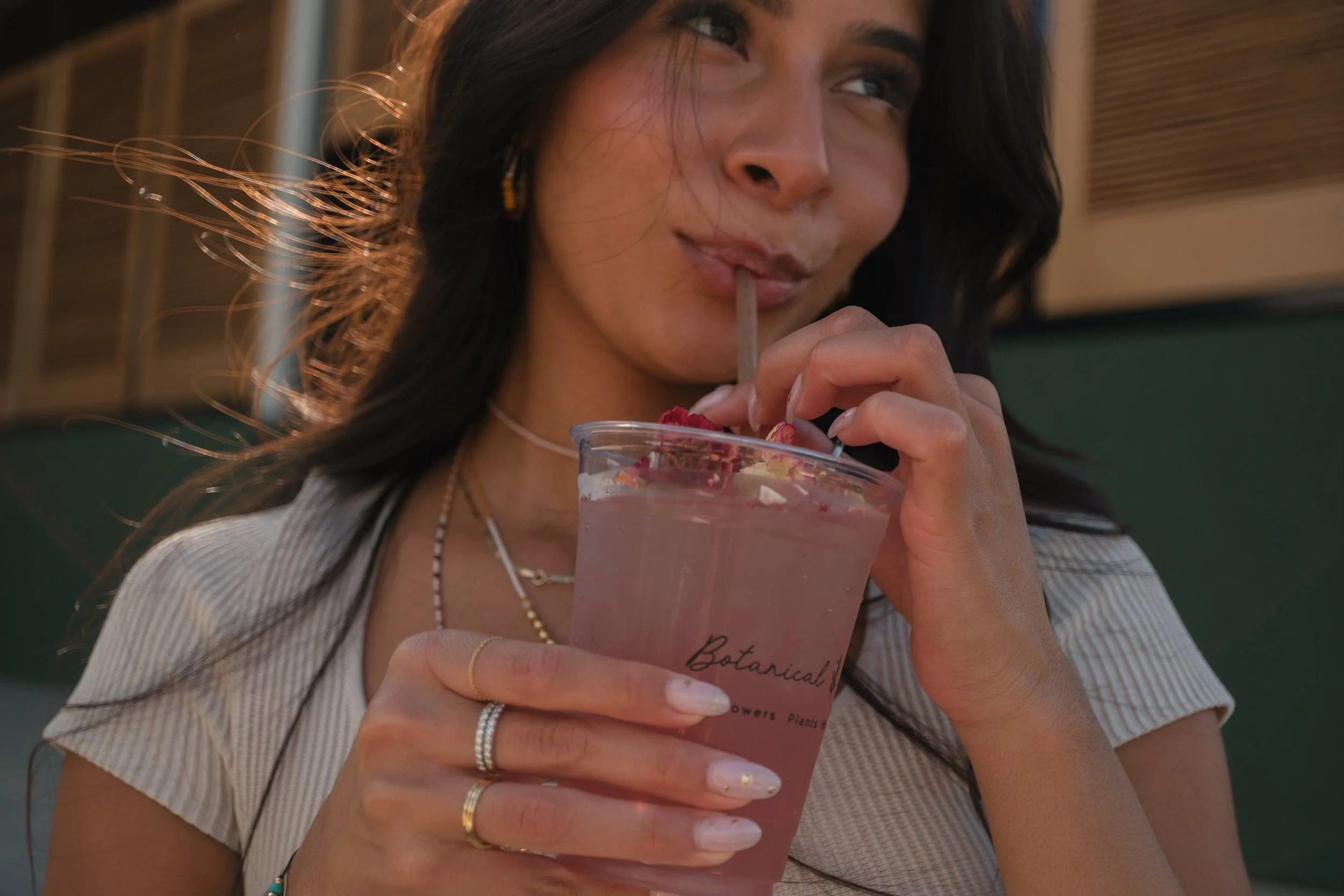 A woman drinking a pink mocktail with edible flowers in it in Charlotte North Carolina