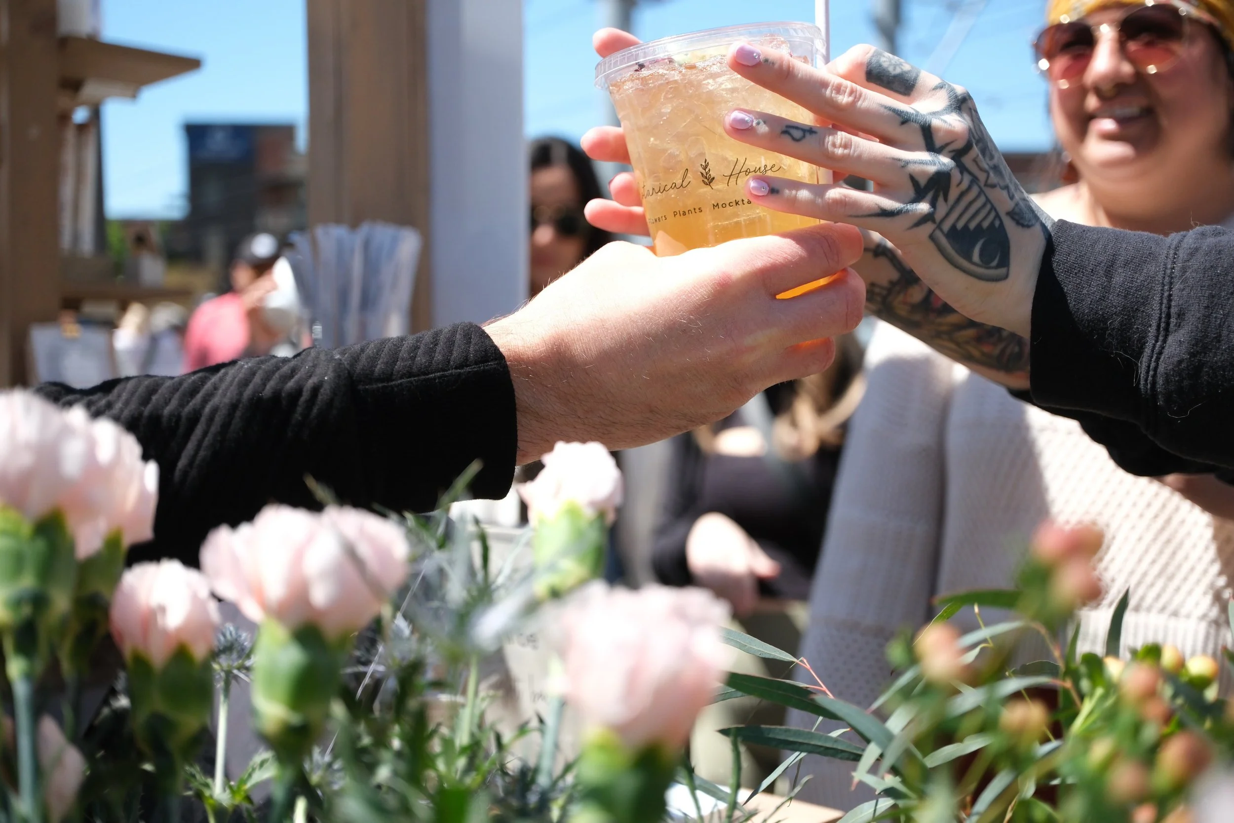 Someone handing anything person a mocktail beverage with edible flowers in it in Charlotte, North Carolina