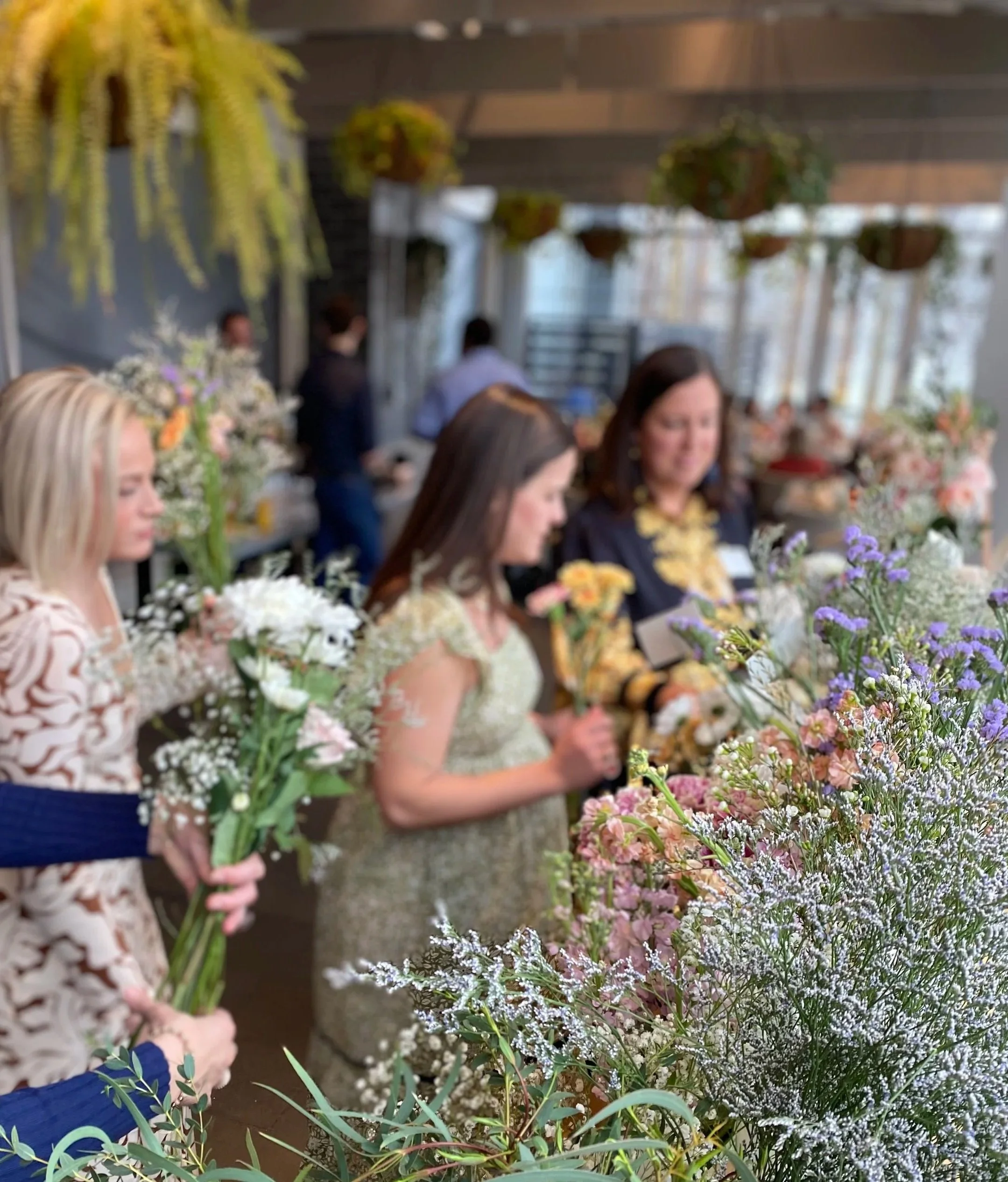 three women pulling flowers from a bouquet bar