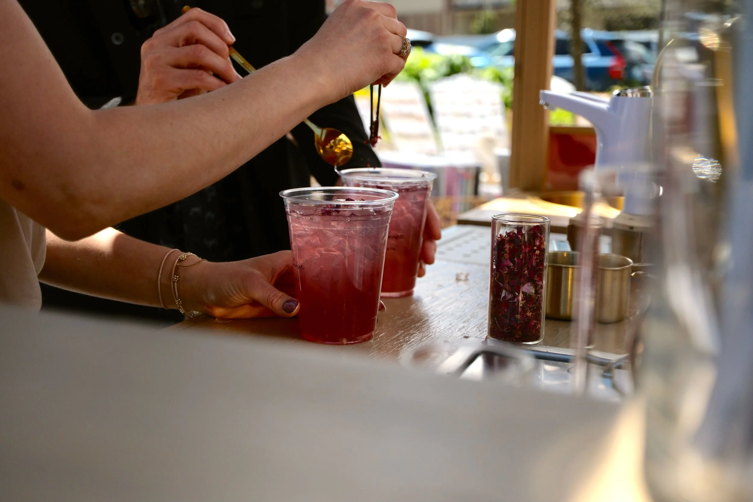 Two people making mocktail beverages and adding edible flow
