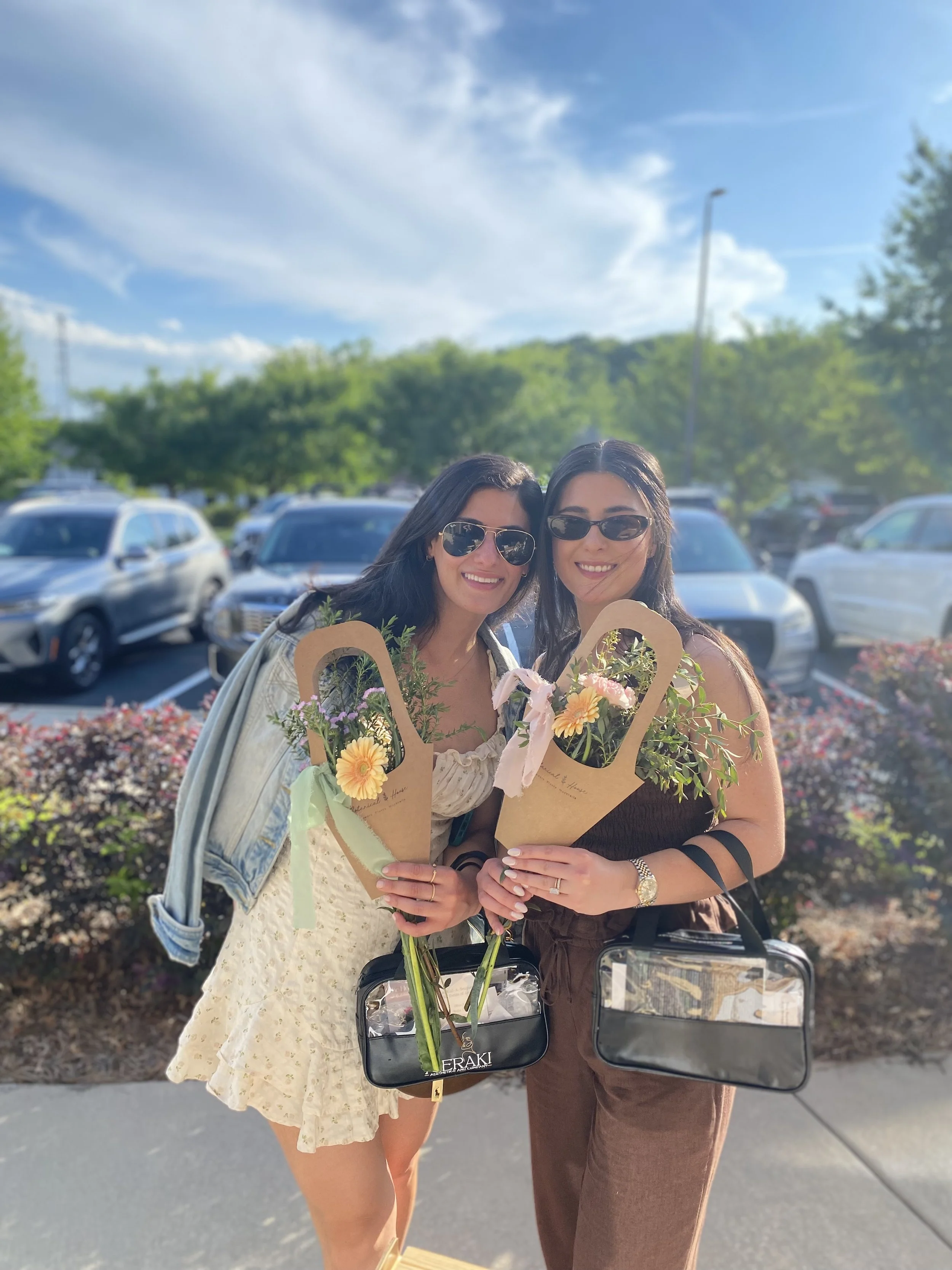 two women outside with sunglasses holding bouquets of flowers they made