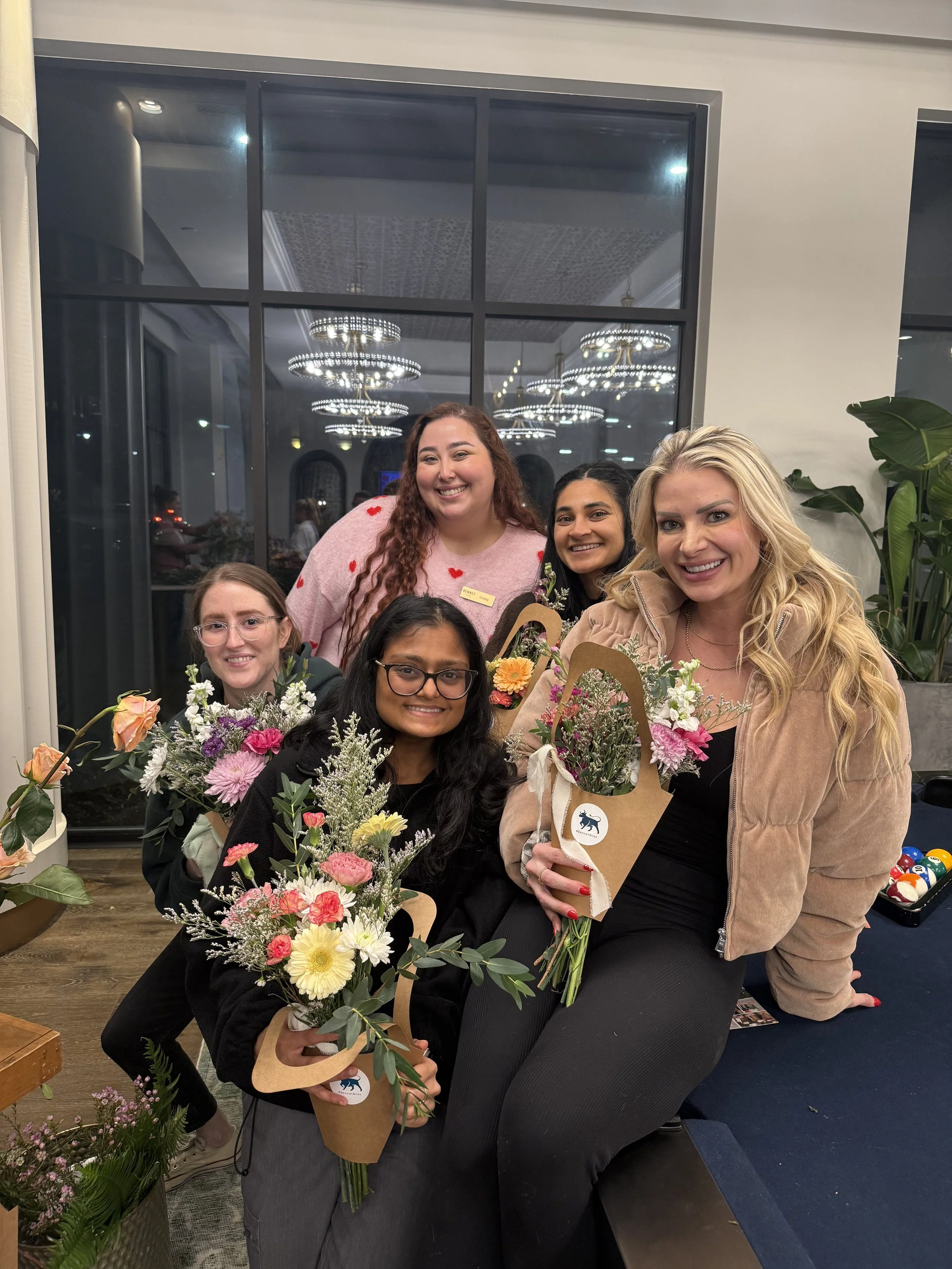 A group of women holding bouquets of flowers they arranged at a flower bar