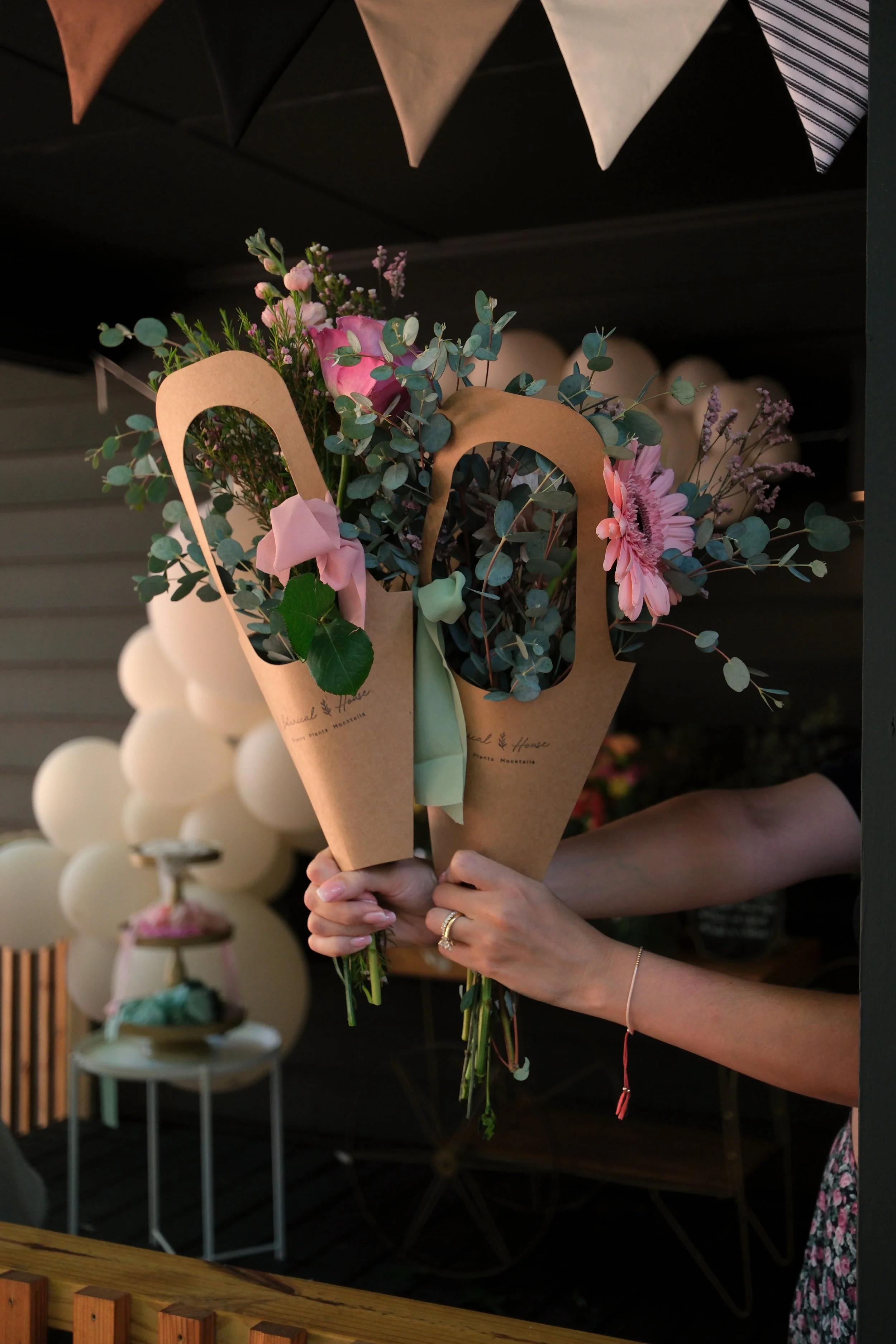 Two hands holding out two bouquets of flowers and eucalyptus made at a flower bar