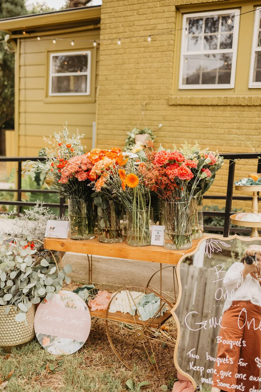 A cart full of flowers, a flower bar, outside of a green building
