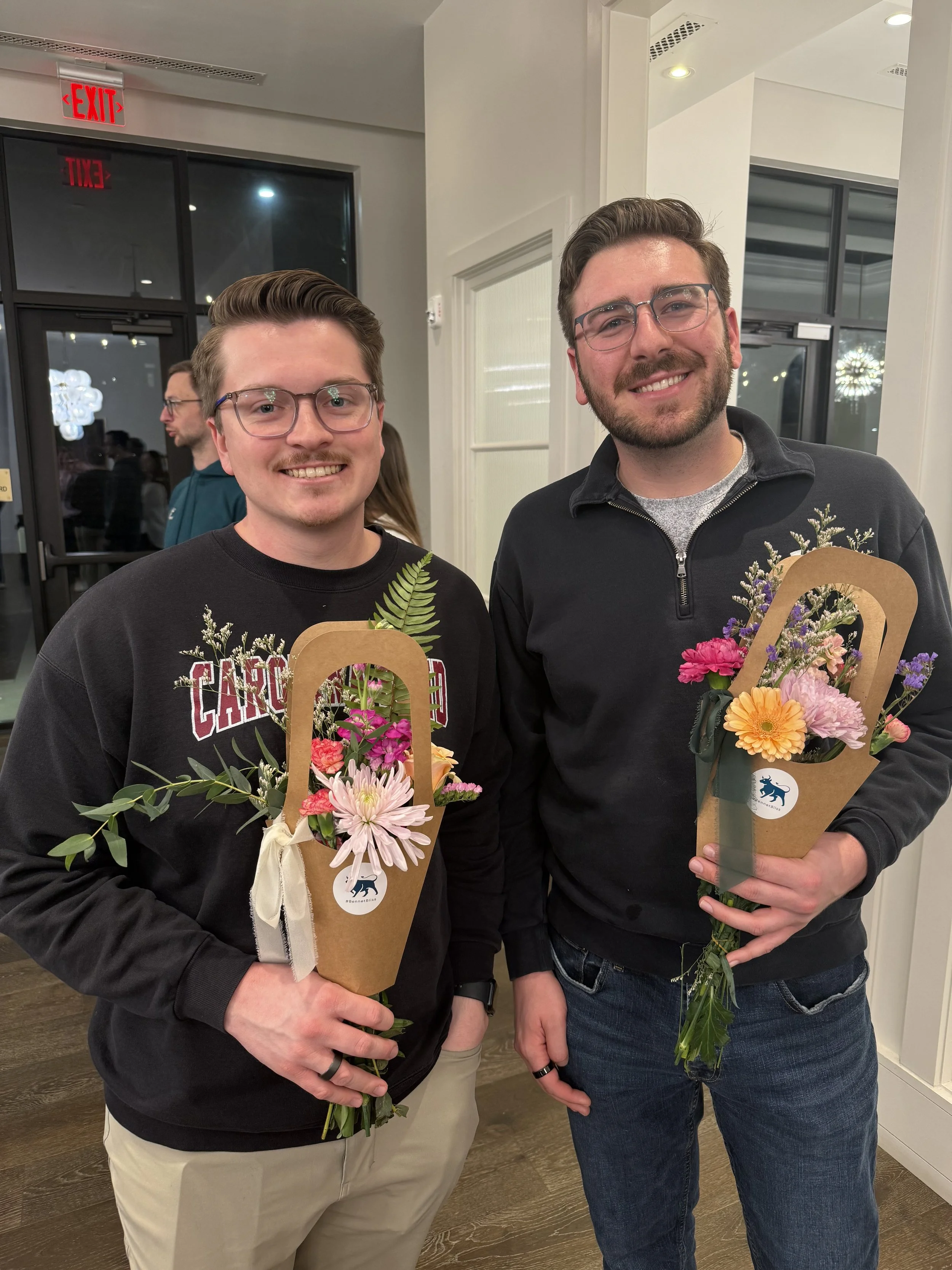 Two men holding bouquets of flowers
