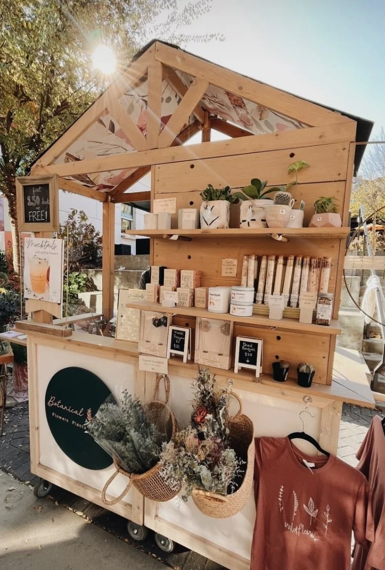 A wooden house shapes market cart full of floral products and eucalyptus