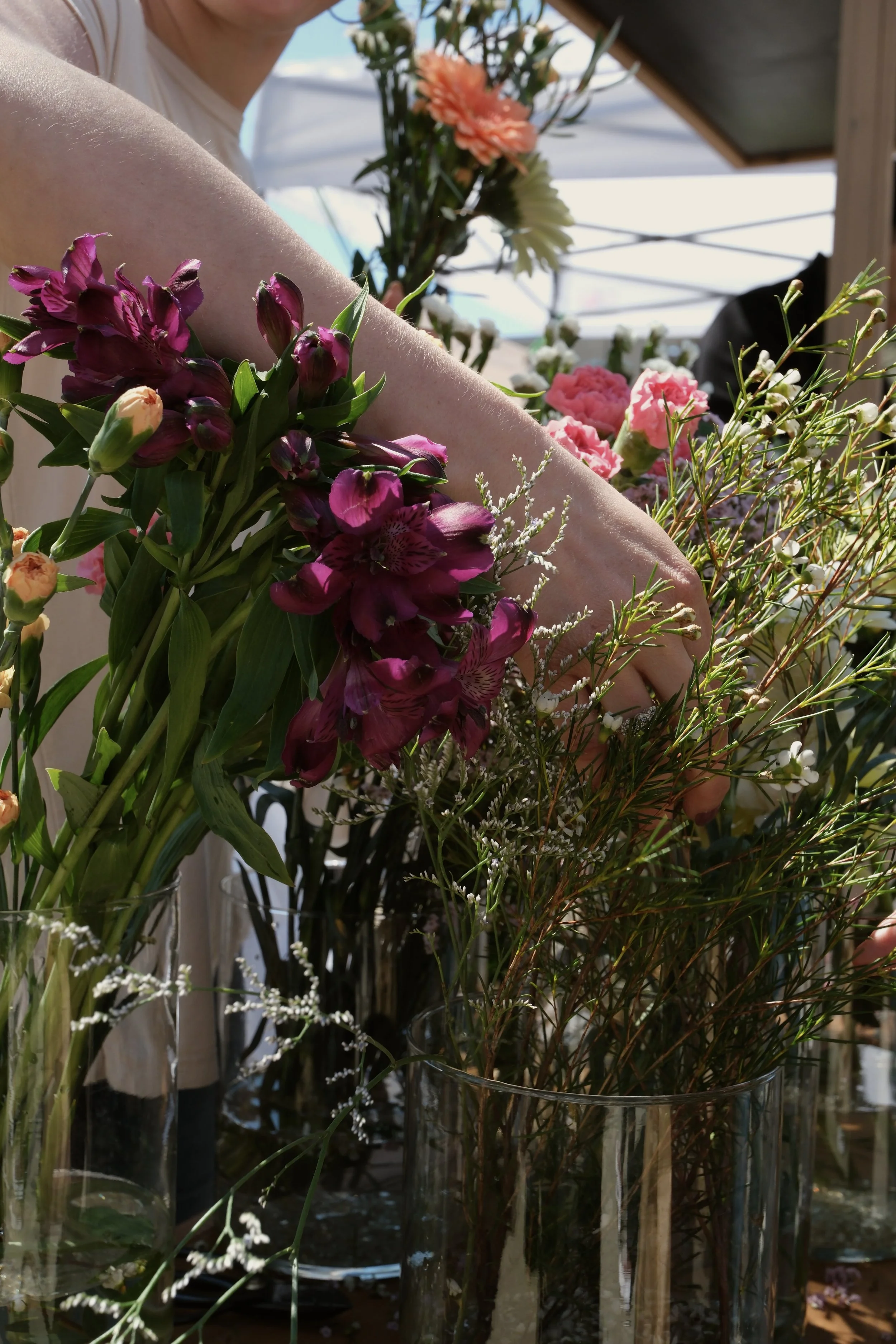 A hand picking flowers out of vases at a flower bar