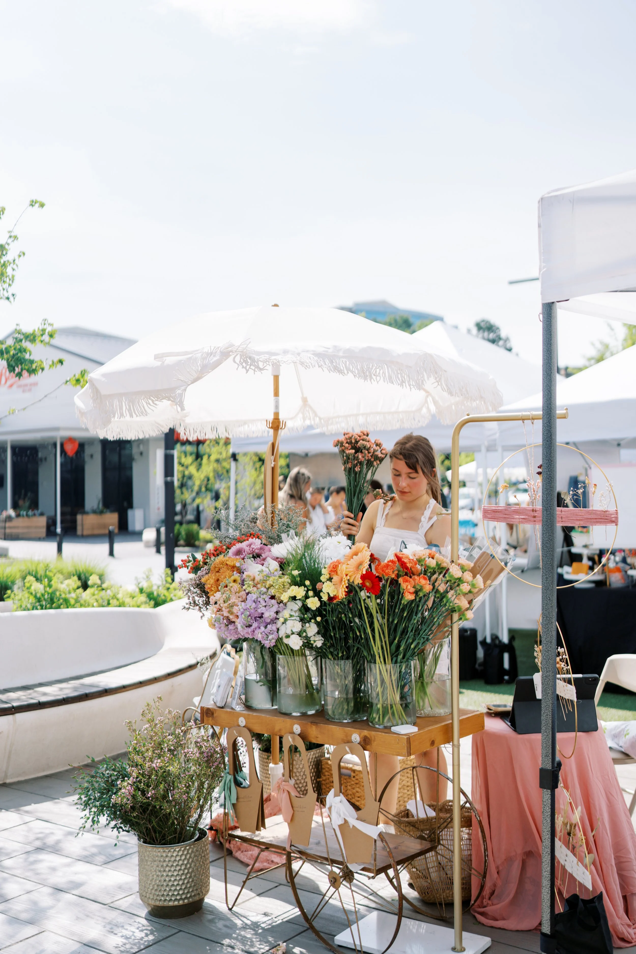 A girl building a bouquet at a cart full of flowers