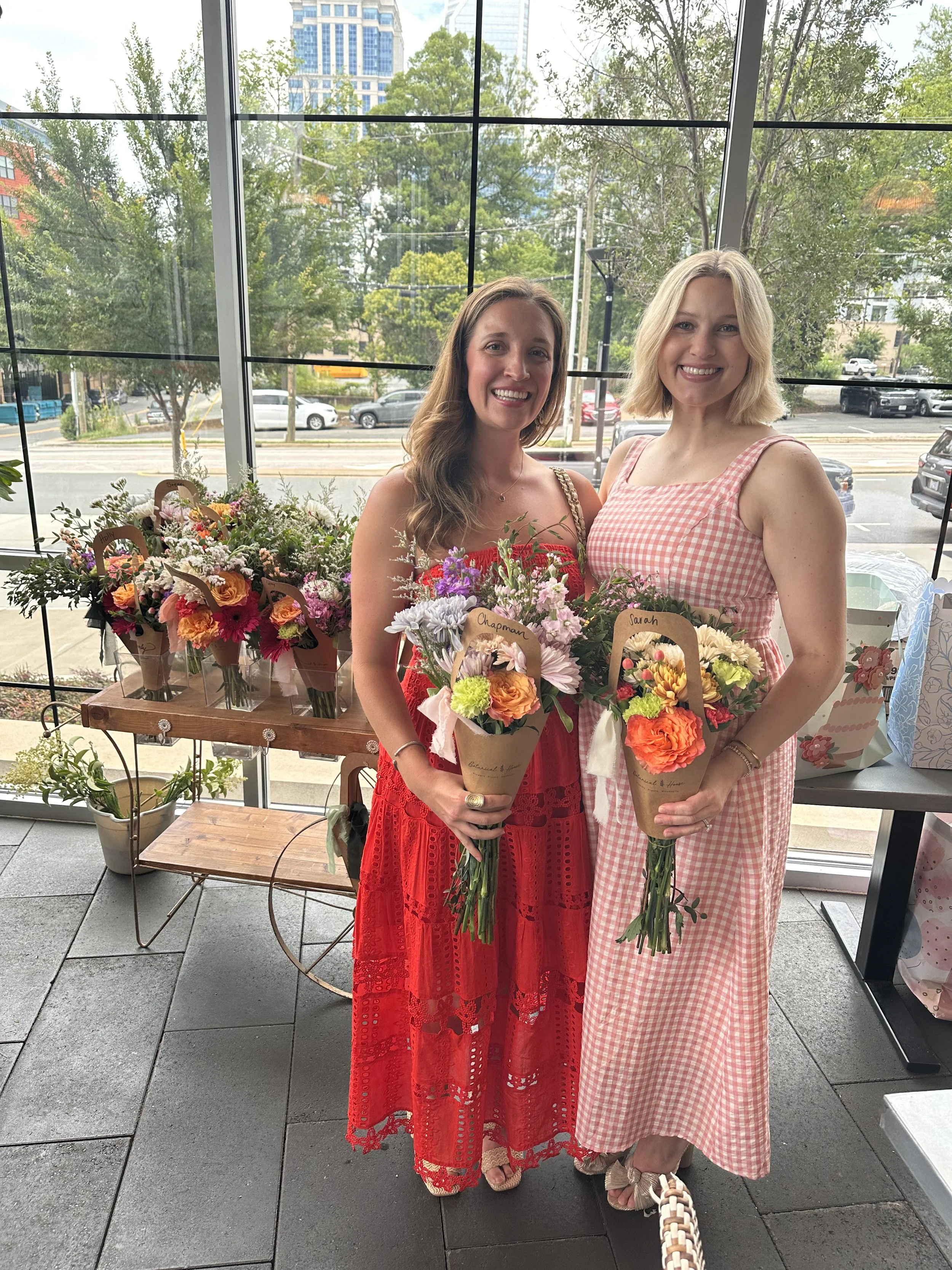 two women at a flower cart in Charlotte with bouquets