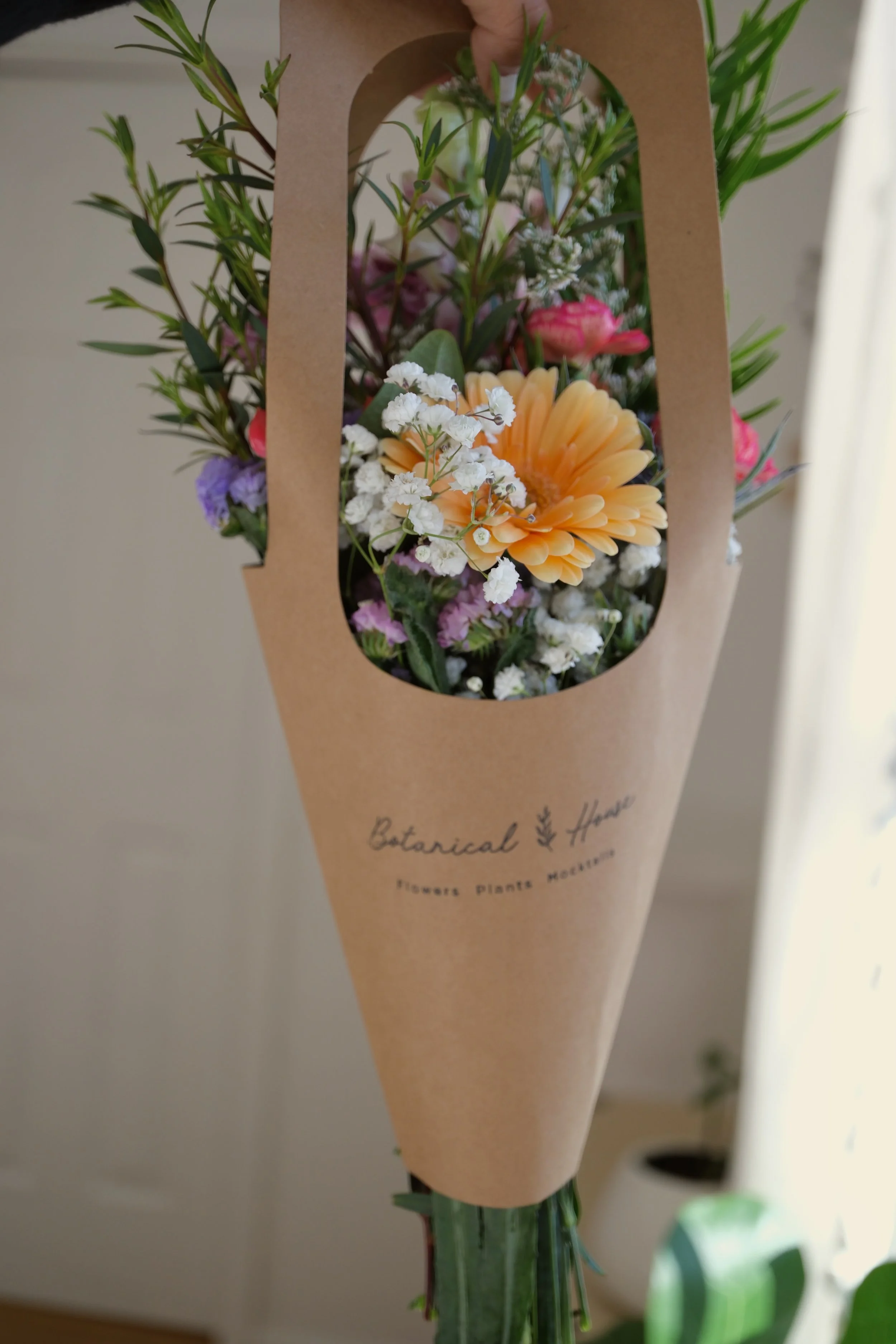 A small bouquet of flowers in a paper bouquet carrier