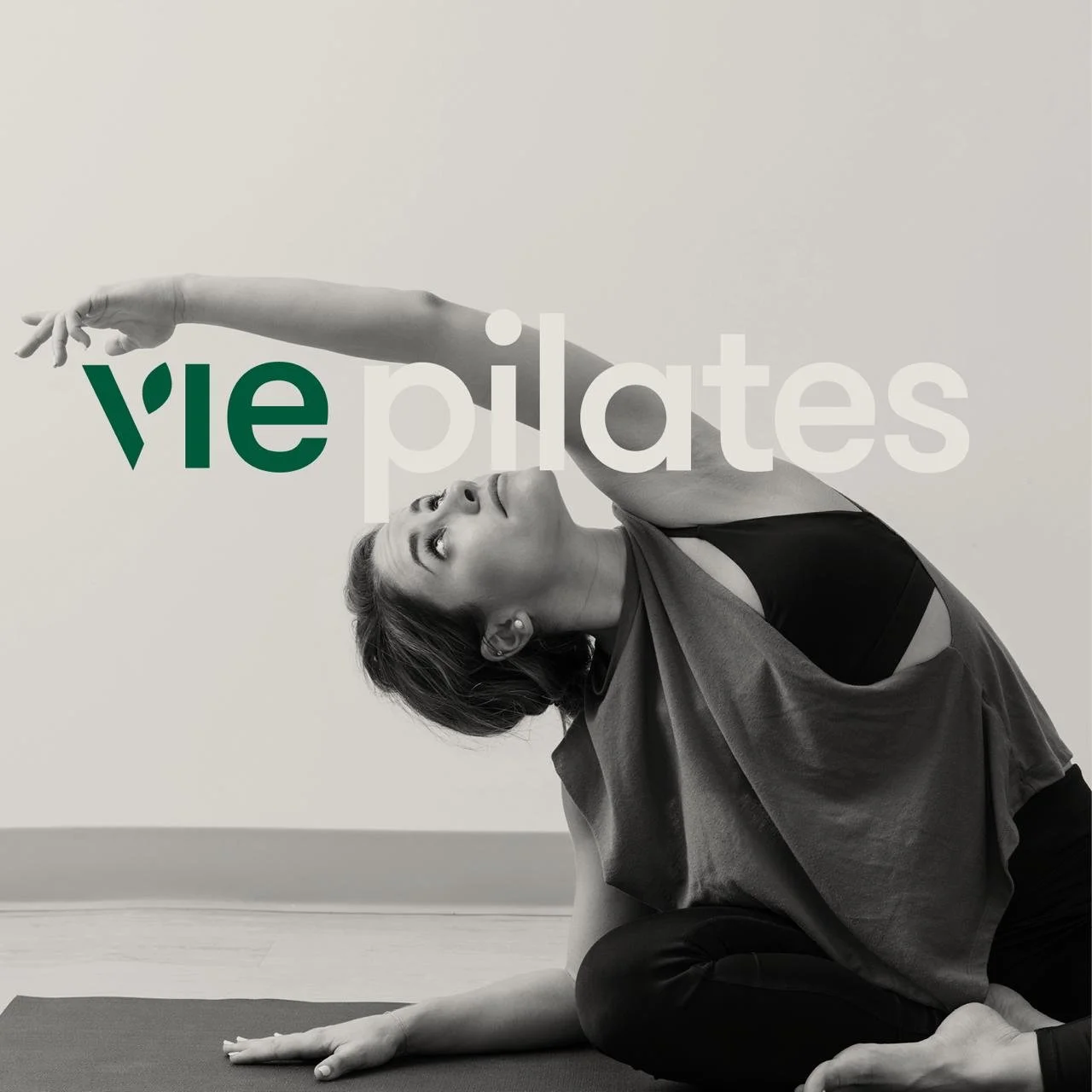 Woman practicing yoga in seated side bend pose on a mat with text overlay reading 'view pilates' in stylized font.