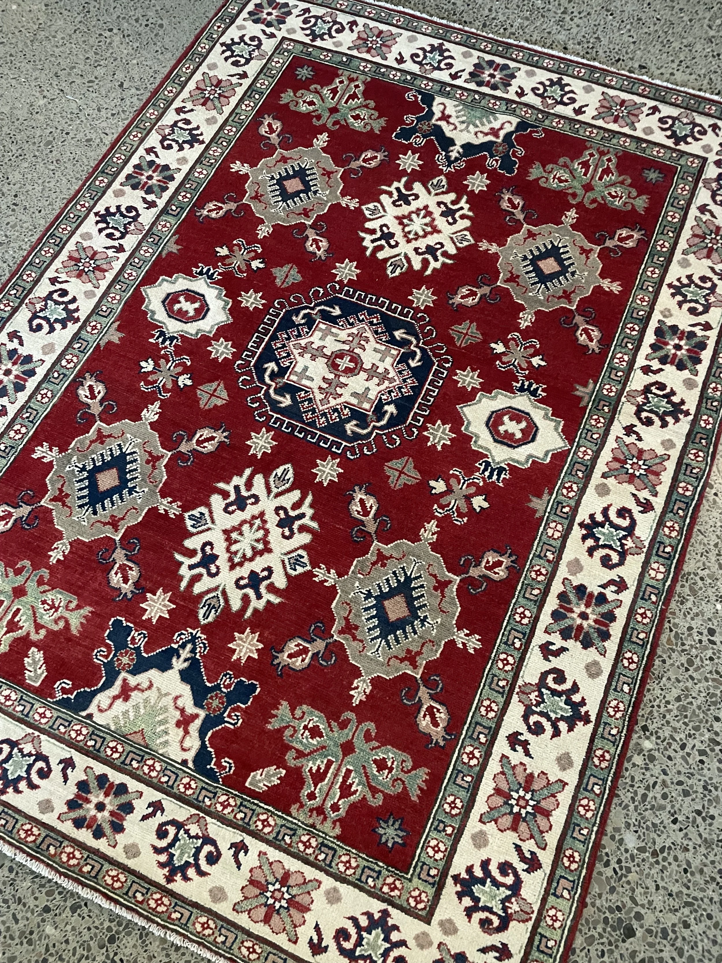A handmade Kazak rug featuring an all-over geometric pattern in a red and cream colour combination.