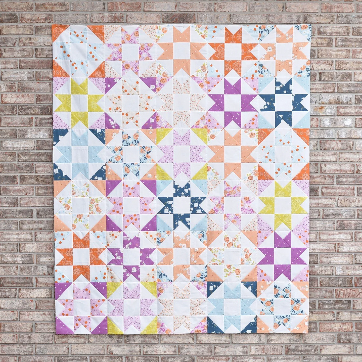 I am so in love with this fabric!! Homage by @cottonandjoy is full of my favorite shades of orange and blue and I'm not even mad about that beautiful shade of purple 🧡💙🩵💜⁠
⁠
I love how it looks sewn up in my latest quilt design, Amberlight II.  T