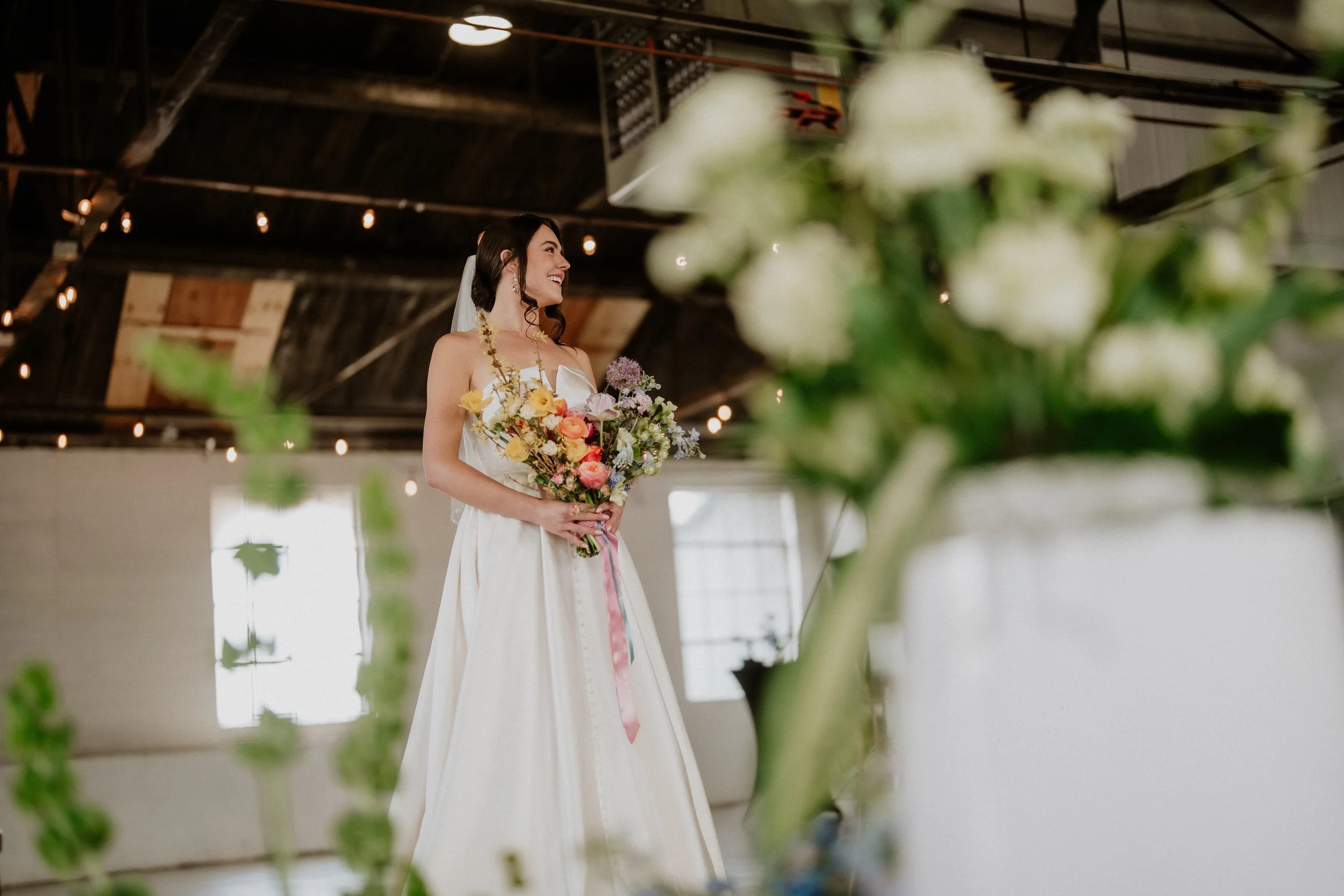 Bride holding a colorful bouquet under string lights at Meanwhile Block