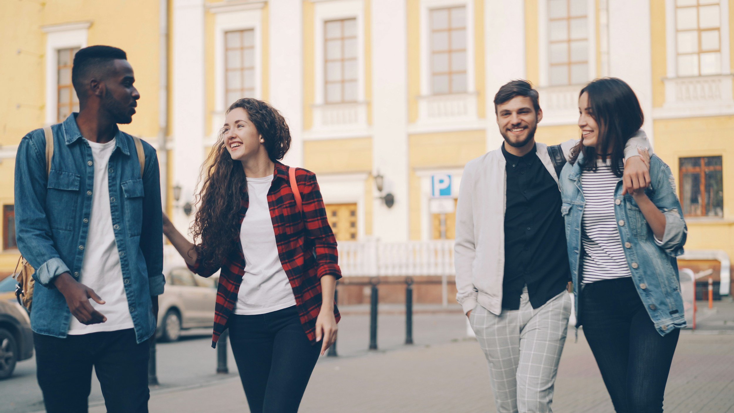 A group of young adult friends walking and talking together on a city street