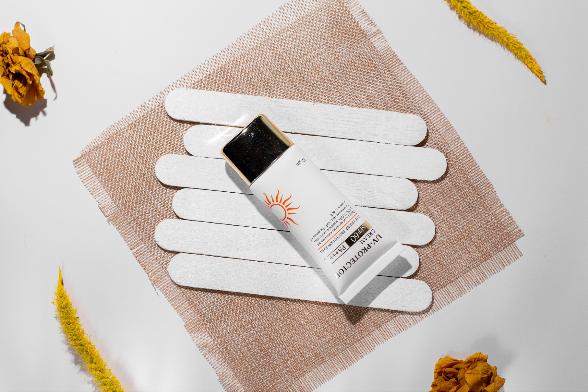 A sunscreen tube is sitting beside flowers