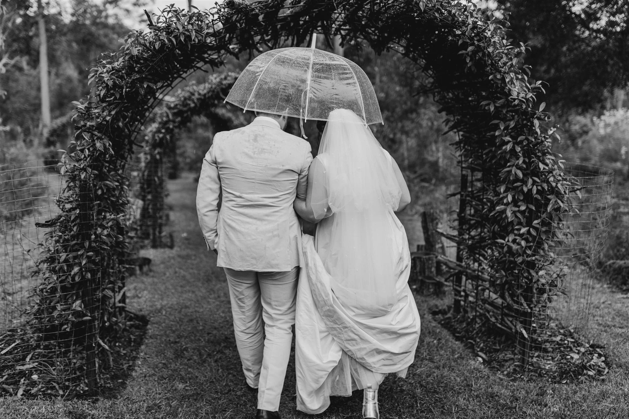 Couple under an umbrella walking through an archway. Photo by Samantha Riles.