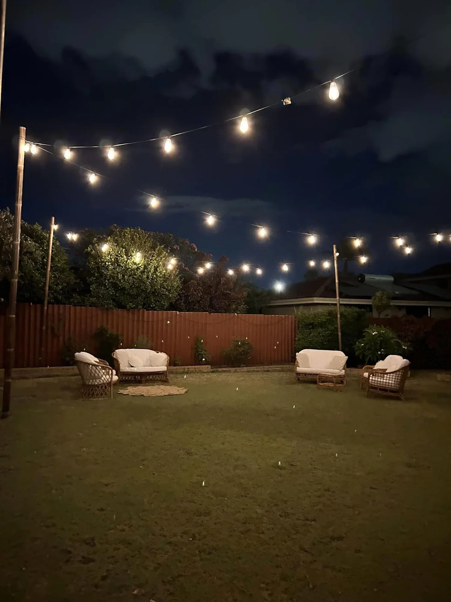 Festoon lighting hire Perth over a backyard wedding dinner table at dusk