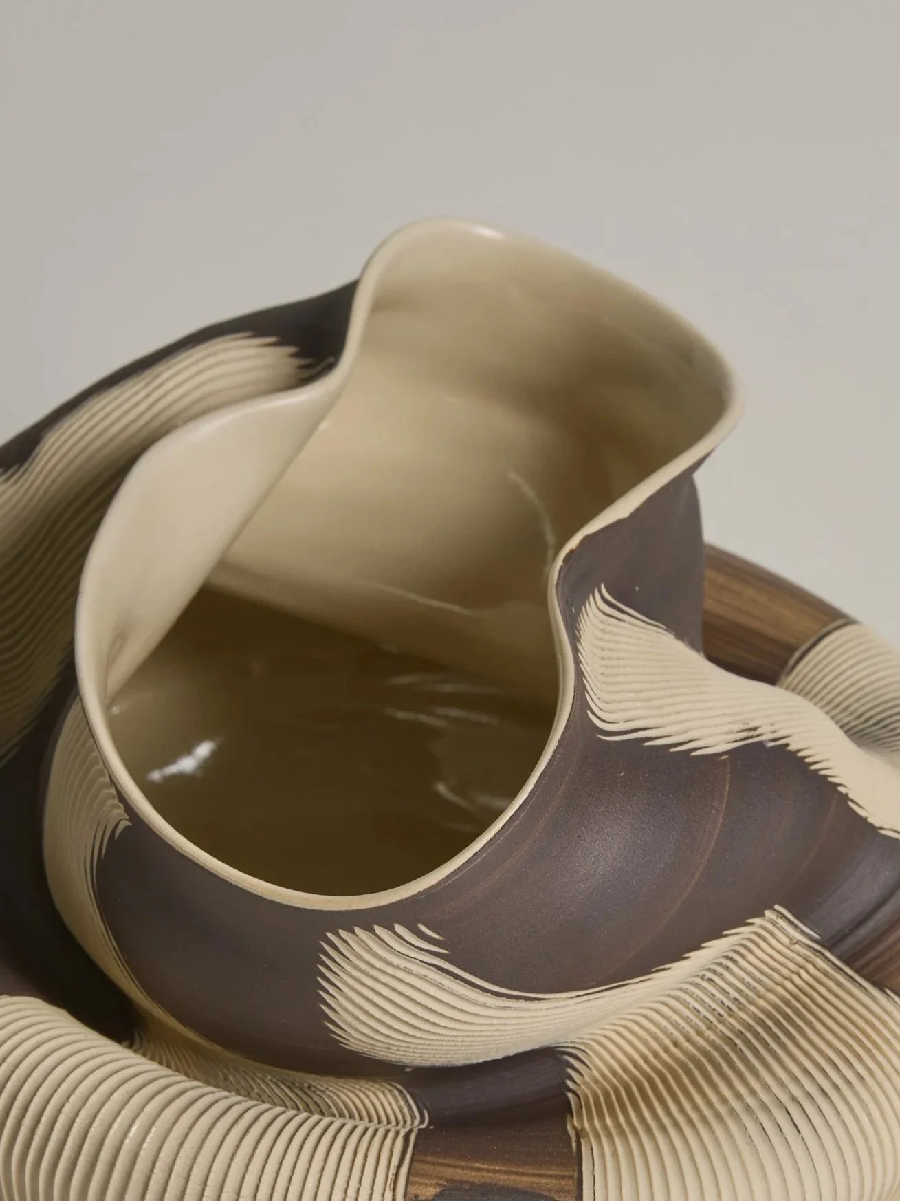 Close-up of a sculptural ceramic vessel by Melbourne ceramic artist Alyssa Nuttall, featuring carved organic forms and layered earthy surfaces.