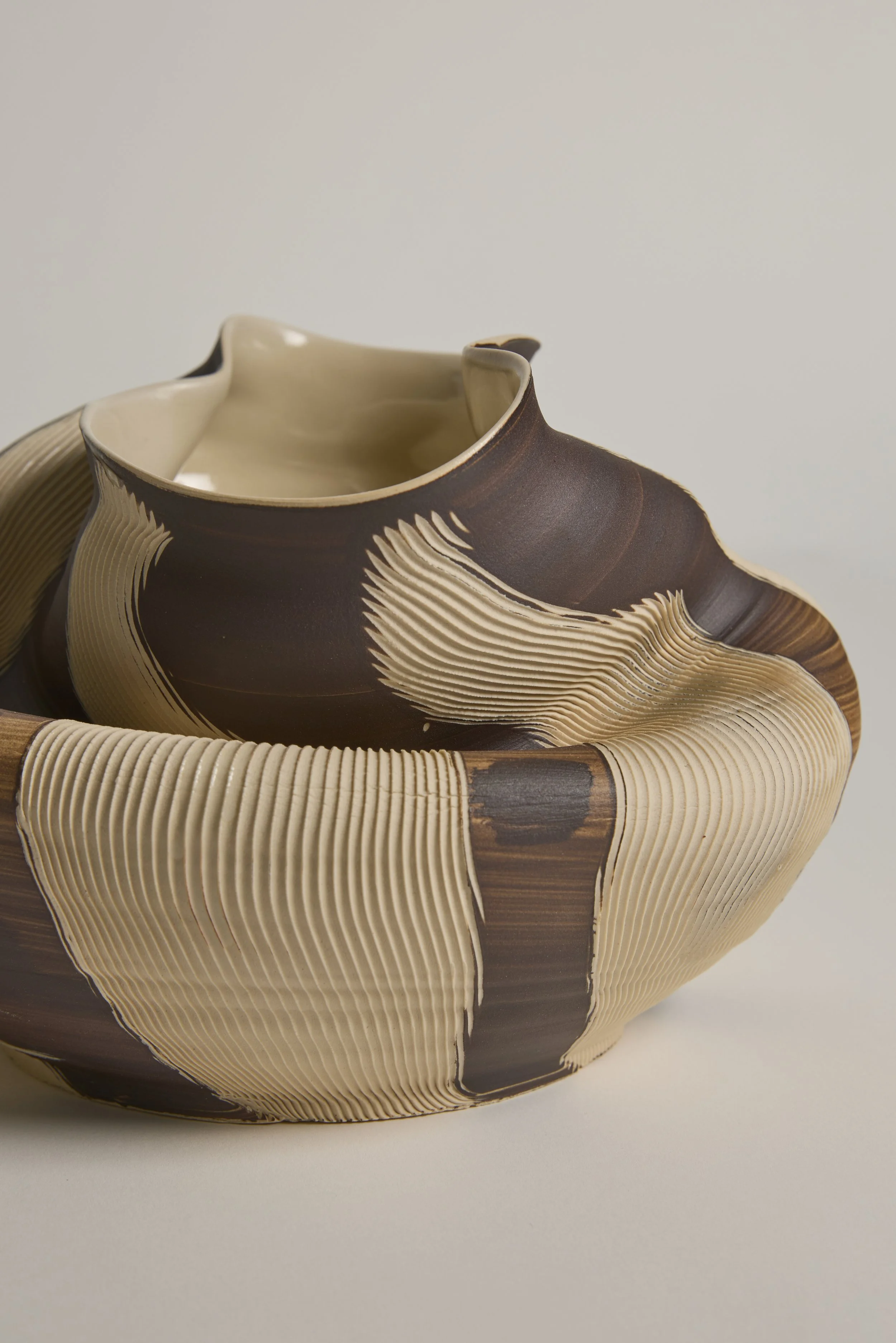 Close-up of a sculptural ceramic vessel by Melbourne ceramic artist Alyssa Nuttall, featuring carved organic forms and layered earthy surfaces.