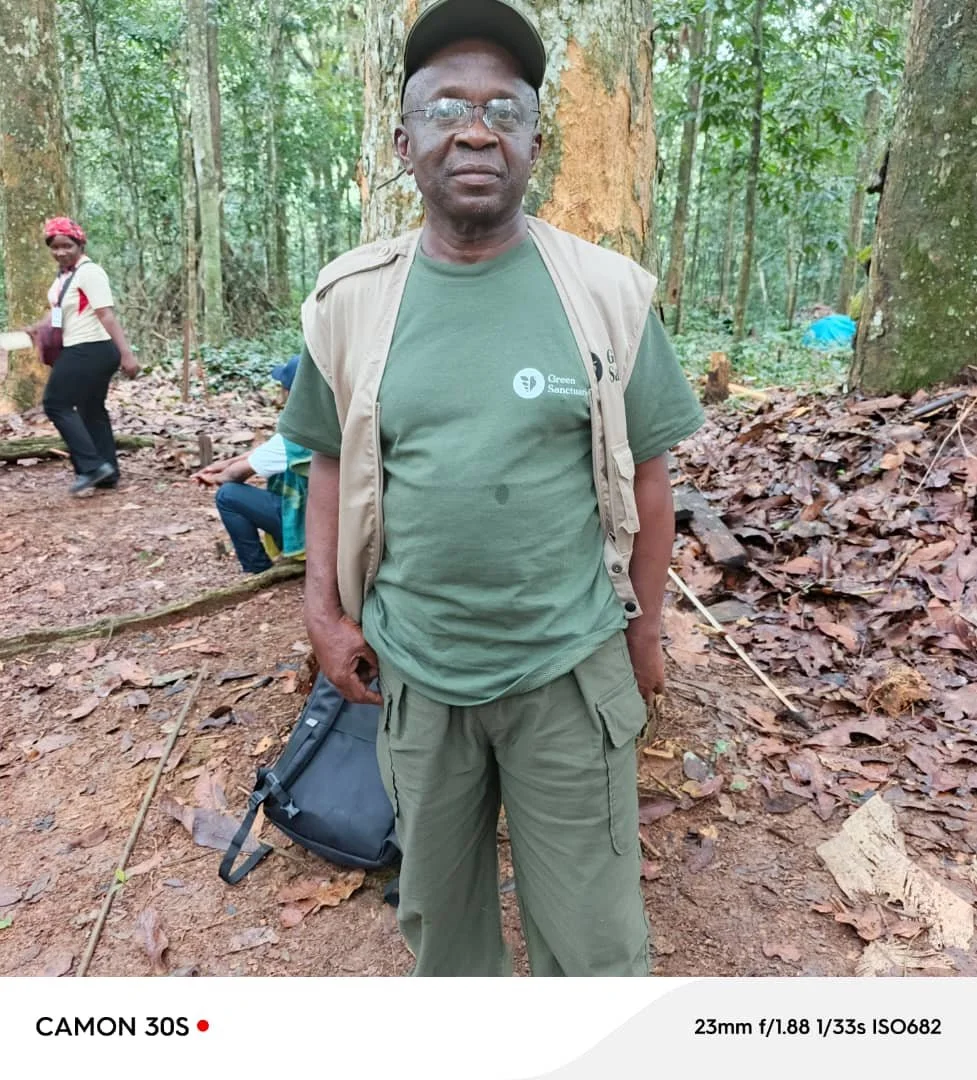 Un homme souriant portant une casquette blanche, entouré d'autres personnes lors d'une activité en plein air.