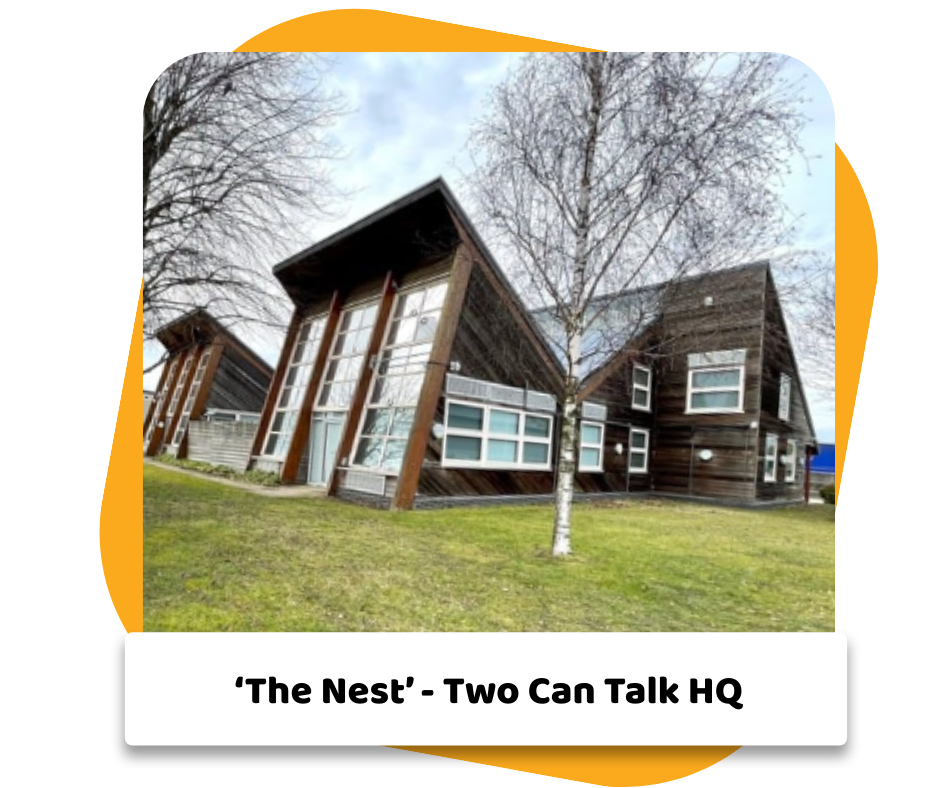 A modern wooden house with large windows, situated on a grassy lawn with a spring tree in front, under a partly cloudy sky.