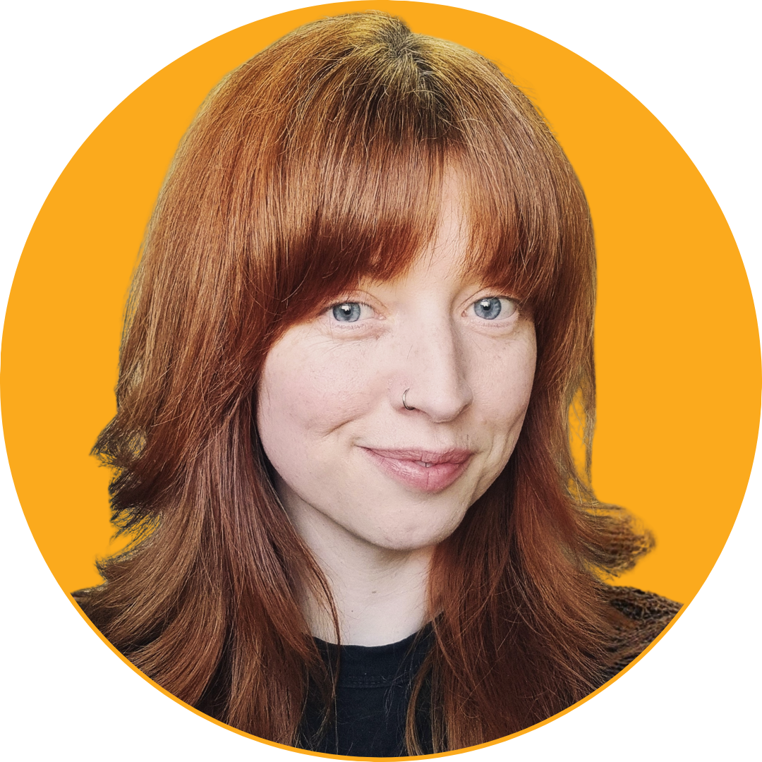 Close-up of a woman with red hair wearing a checkered top against a yellow background.
