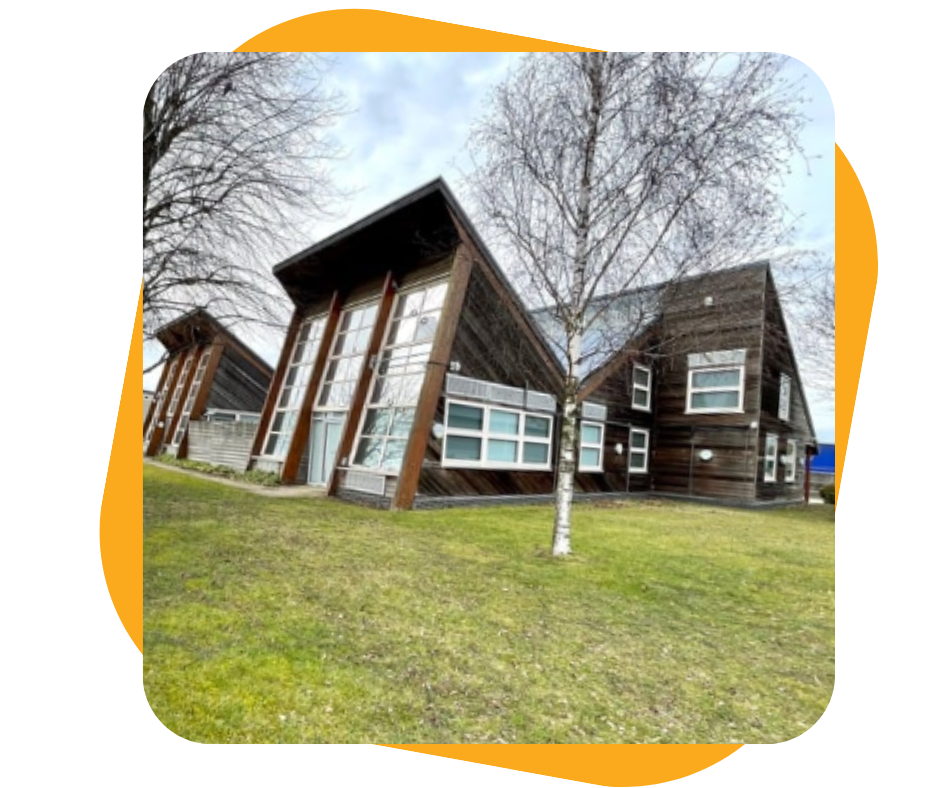 View of modern multi-story wooden houses with large windows, grassy yard, and leafless trees, under a partly cloudy sky.