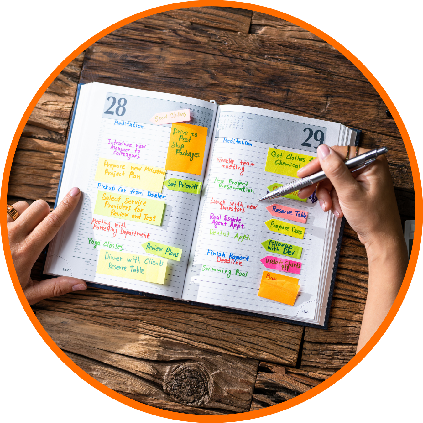 Open planner with handwritten notes and color-coded sticky notes on wooden surface.