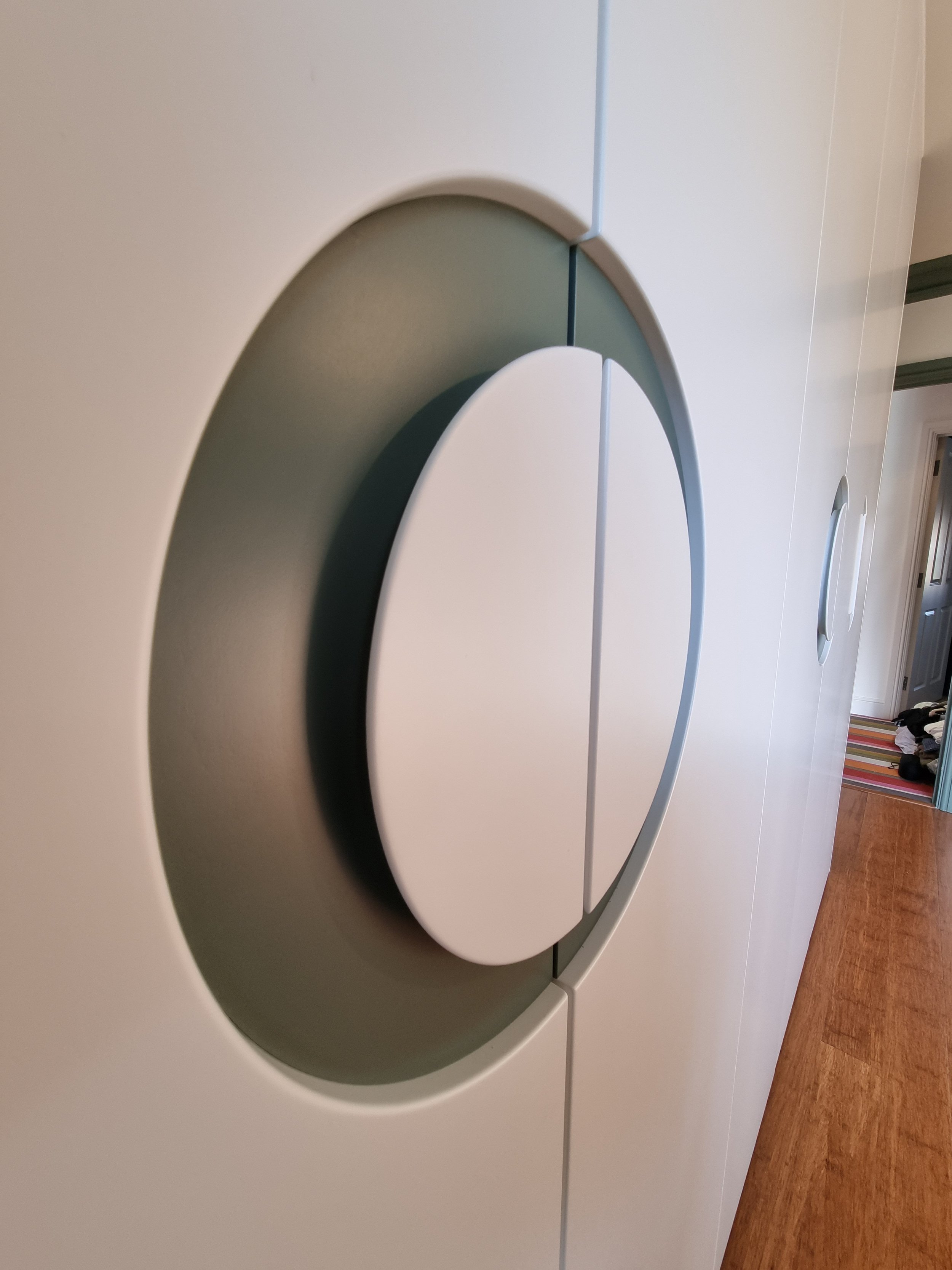 Close-up of a modern, circular door handle on a white door in a house.