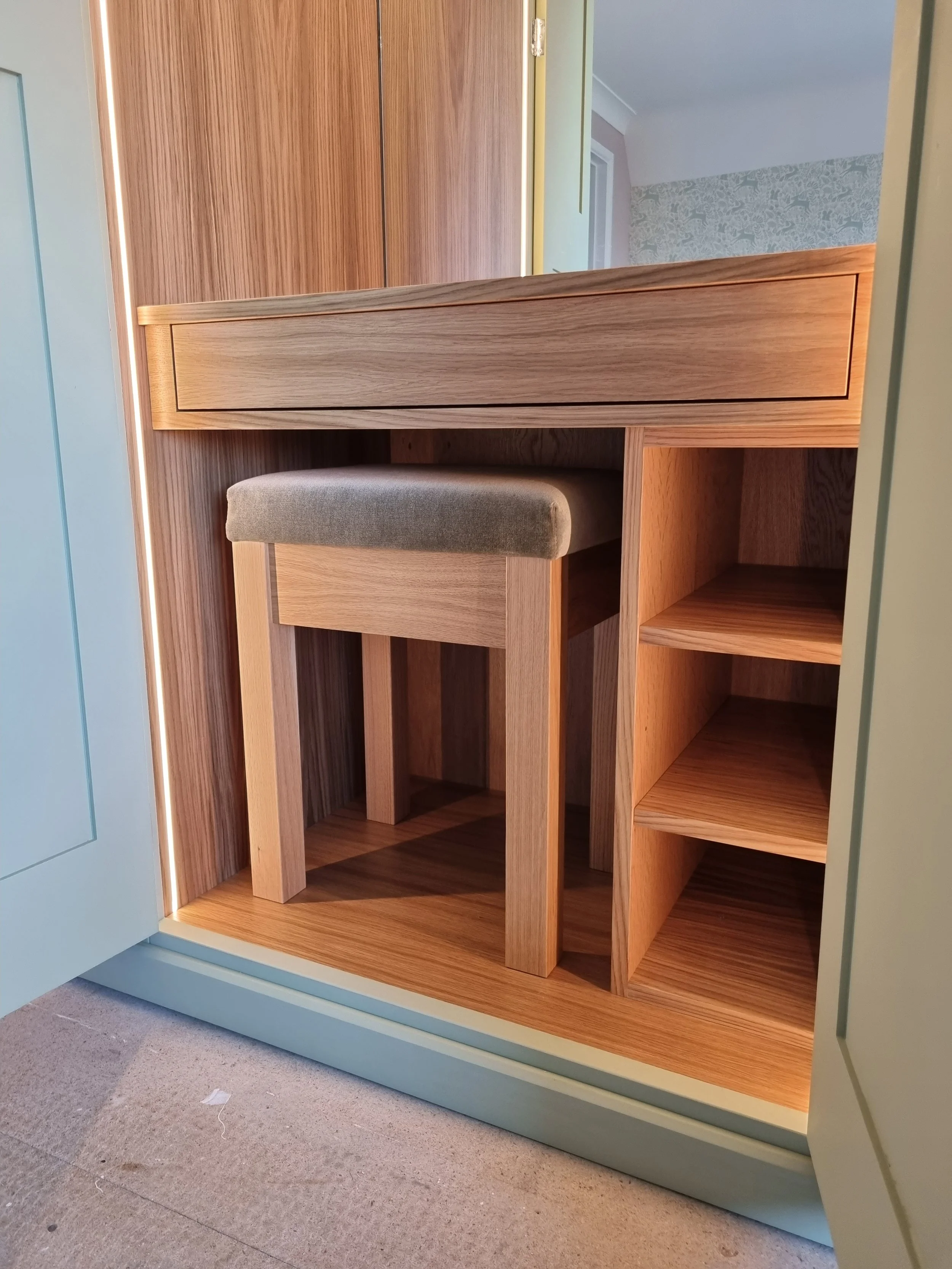 Under-cabinet space with a stool, wooden shelves, and cabinetry in a kitchen or similar space.