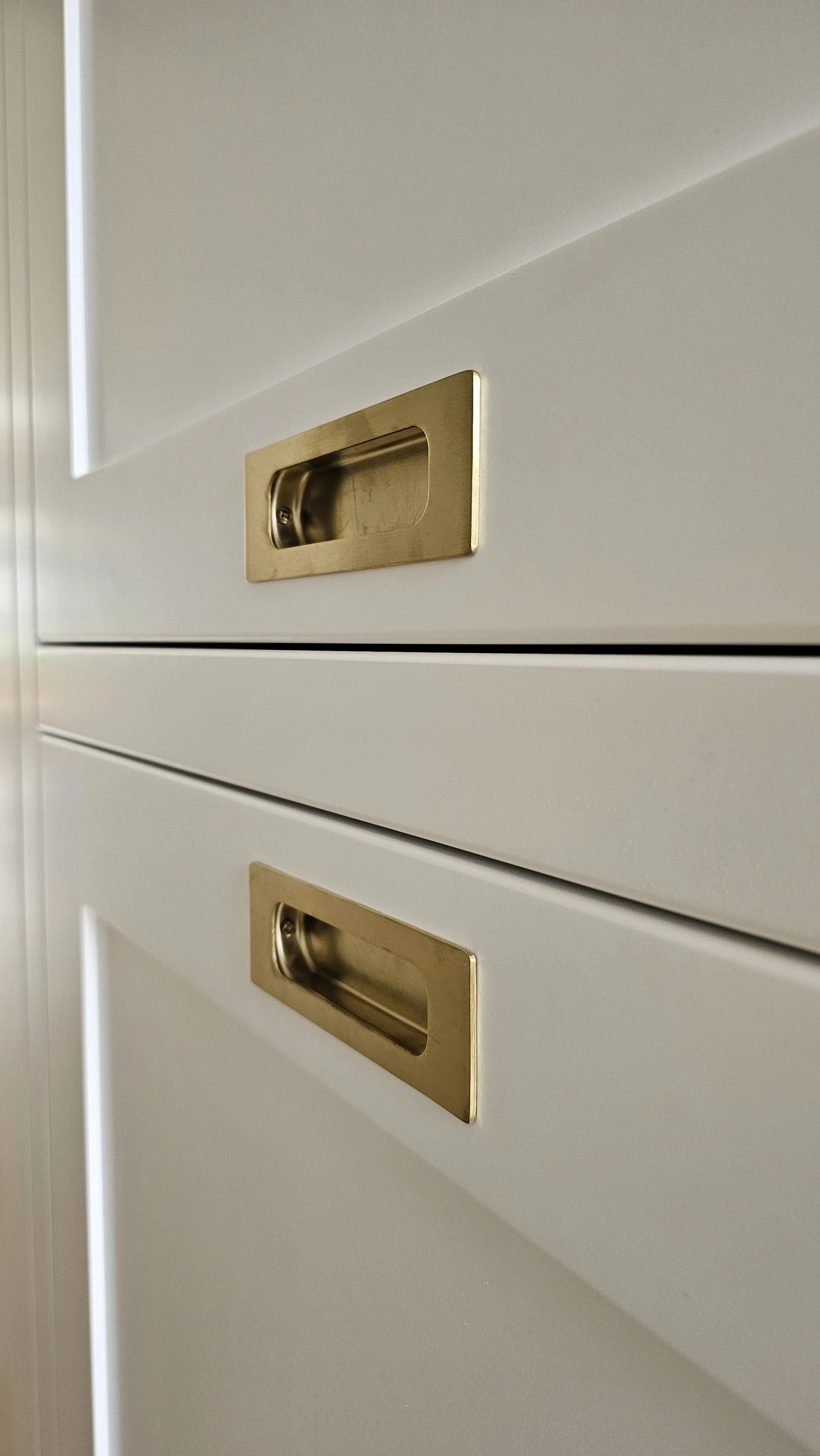 Close-up of white file cabinet drawers with gold-colored handles.