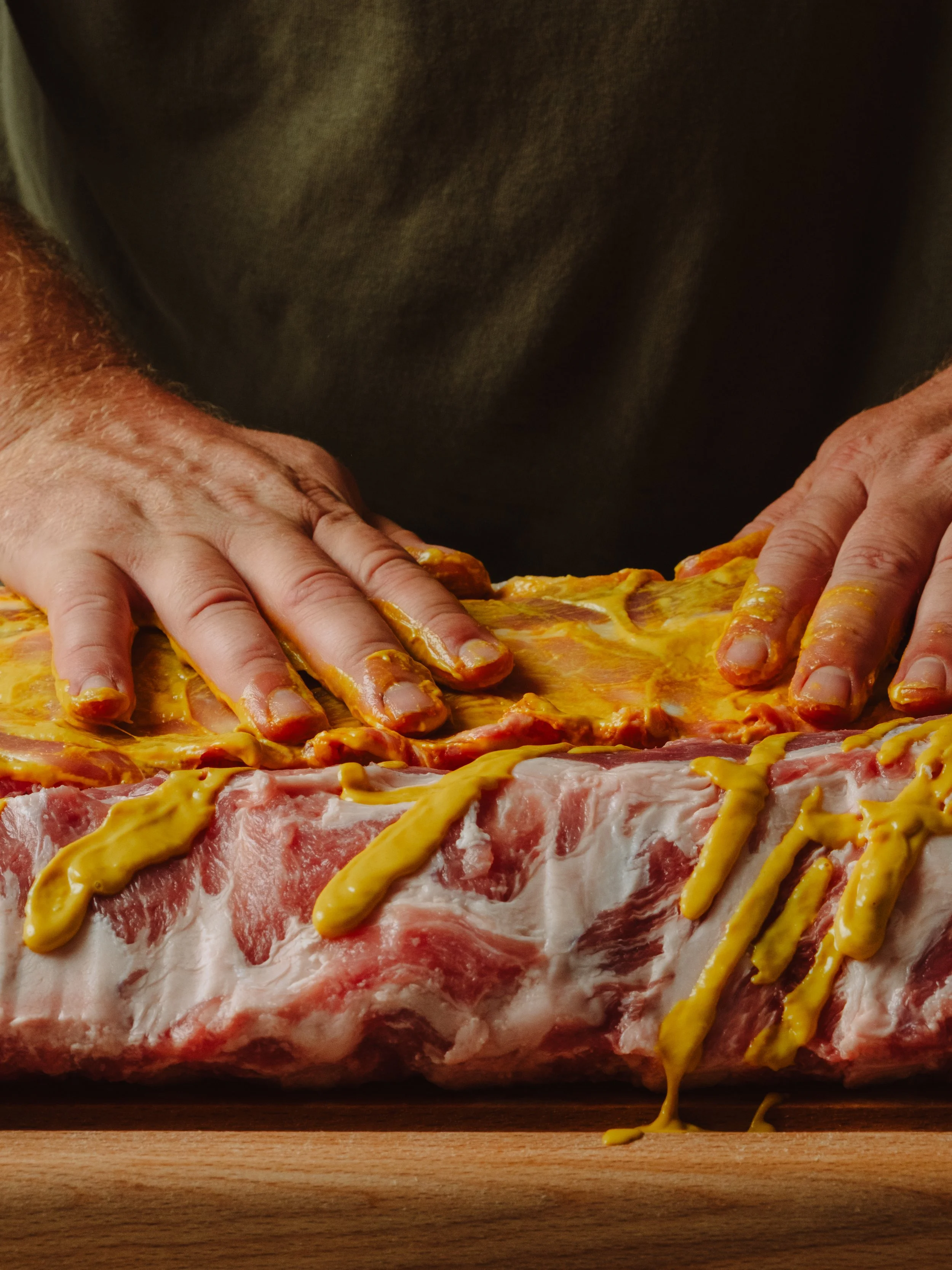 Mustard being used as a binder on baby back ribs
