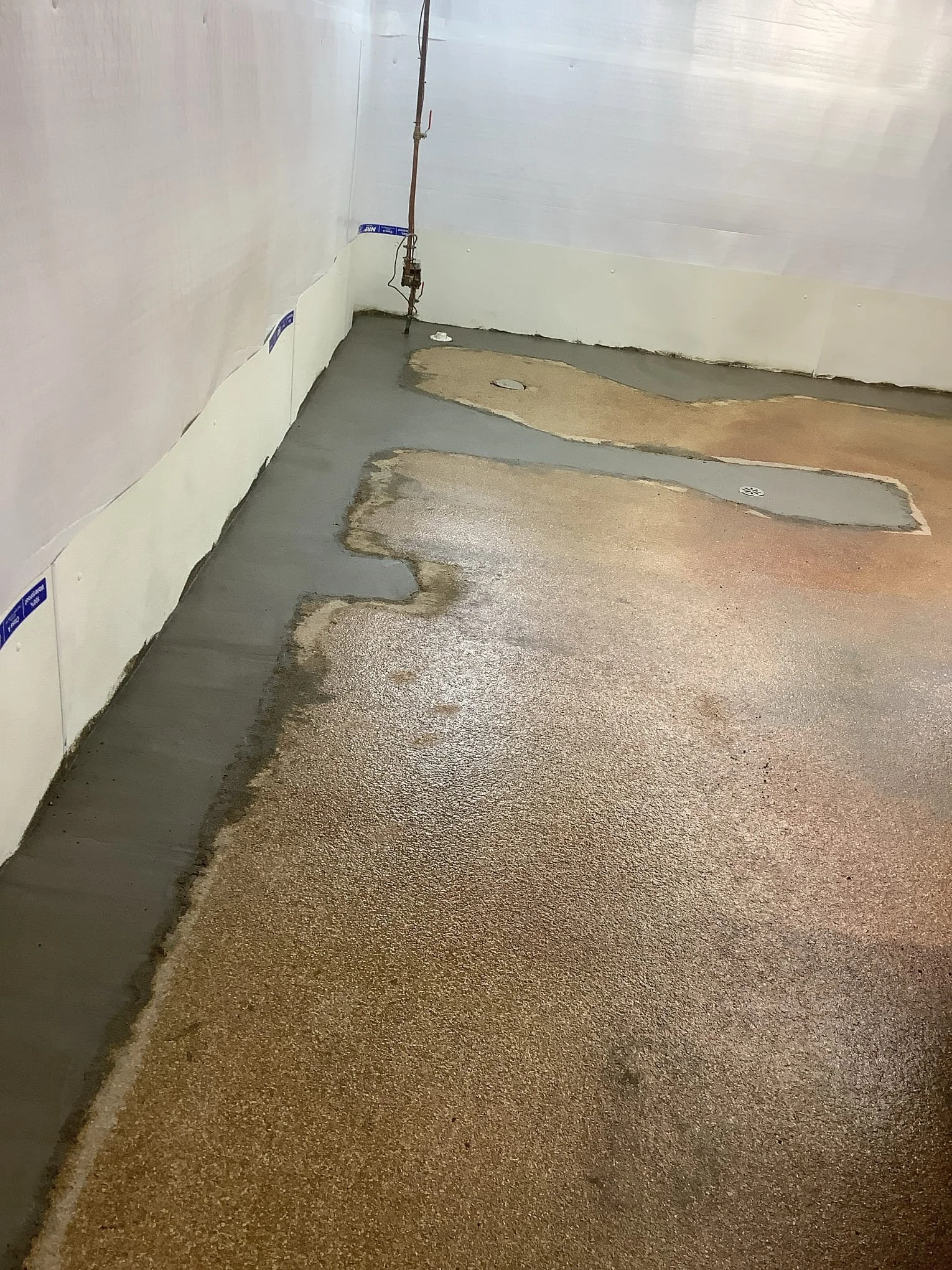 Completed basement waterproofing system in Fraser, Michigan with drain tile, sump pump, and vapor barrier installed.