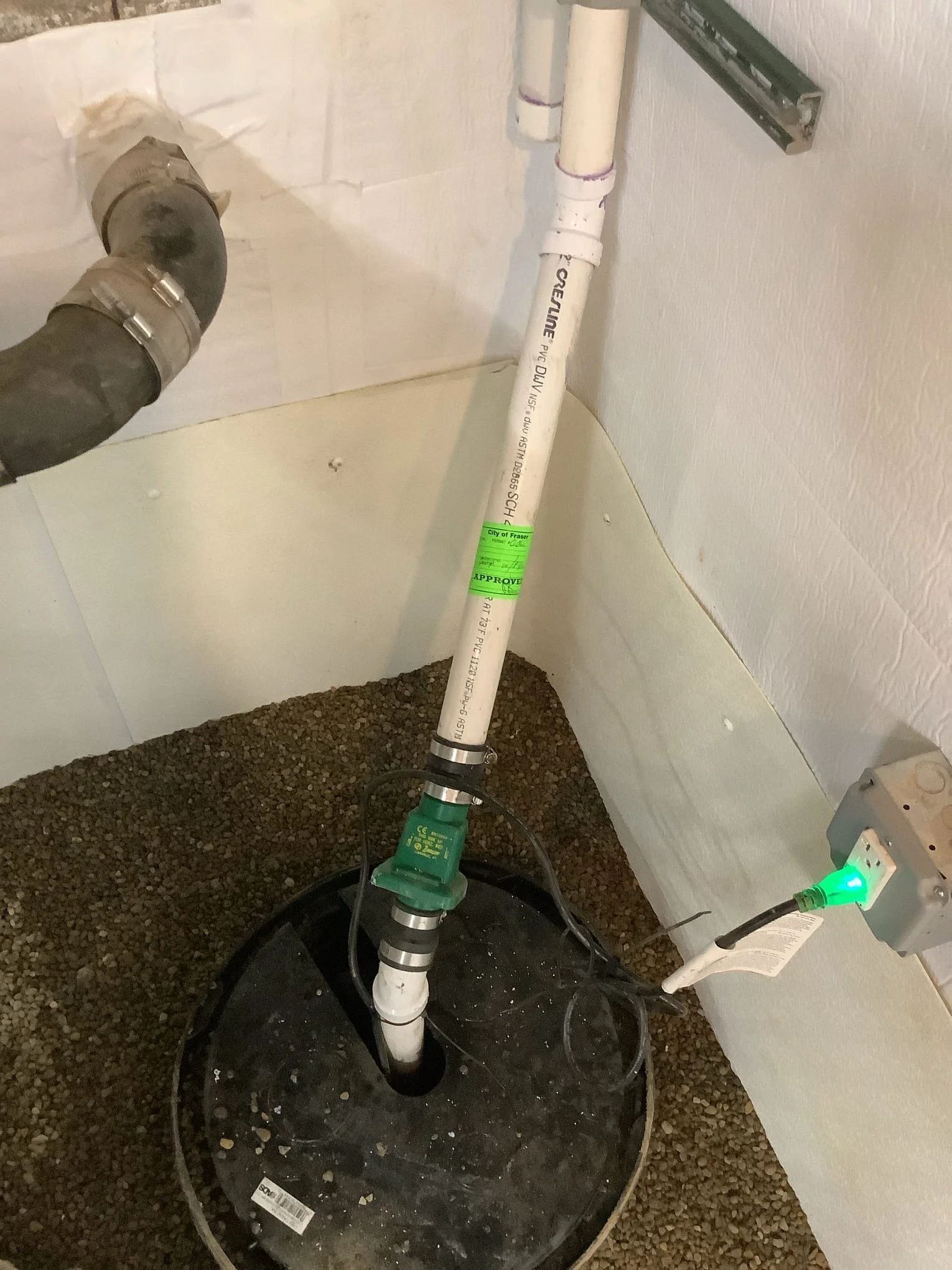 Completed basement waterproofing system in Fraser, Michigan with drain tile, sump pump, and vapor barrier installed.