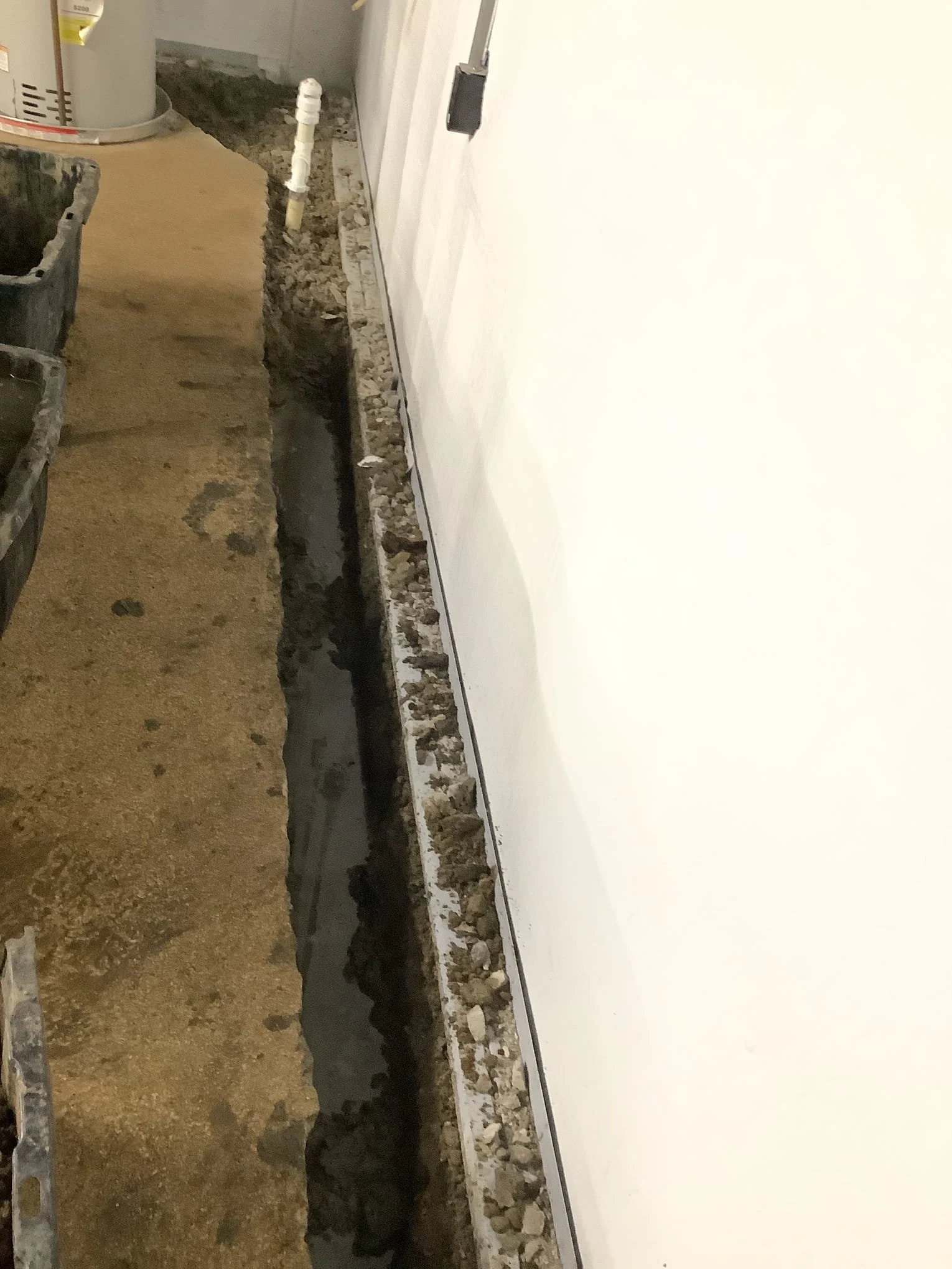 Completed basement waterproofing system in Fraser, Michigan with drain tile, sump pump, and vapor barrier installed.