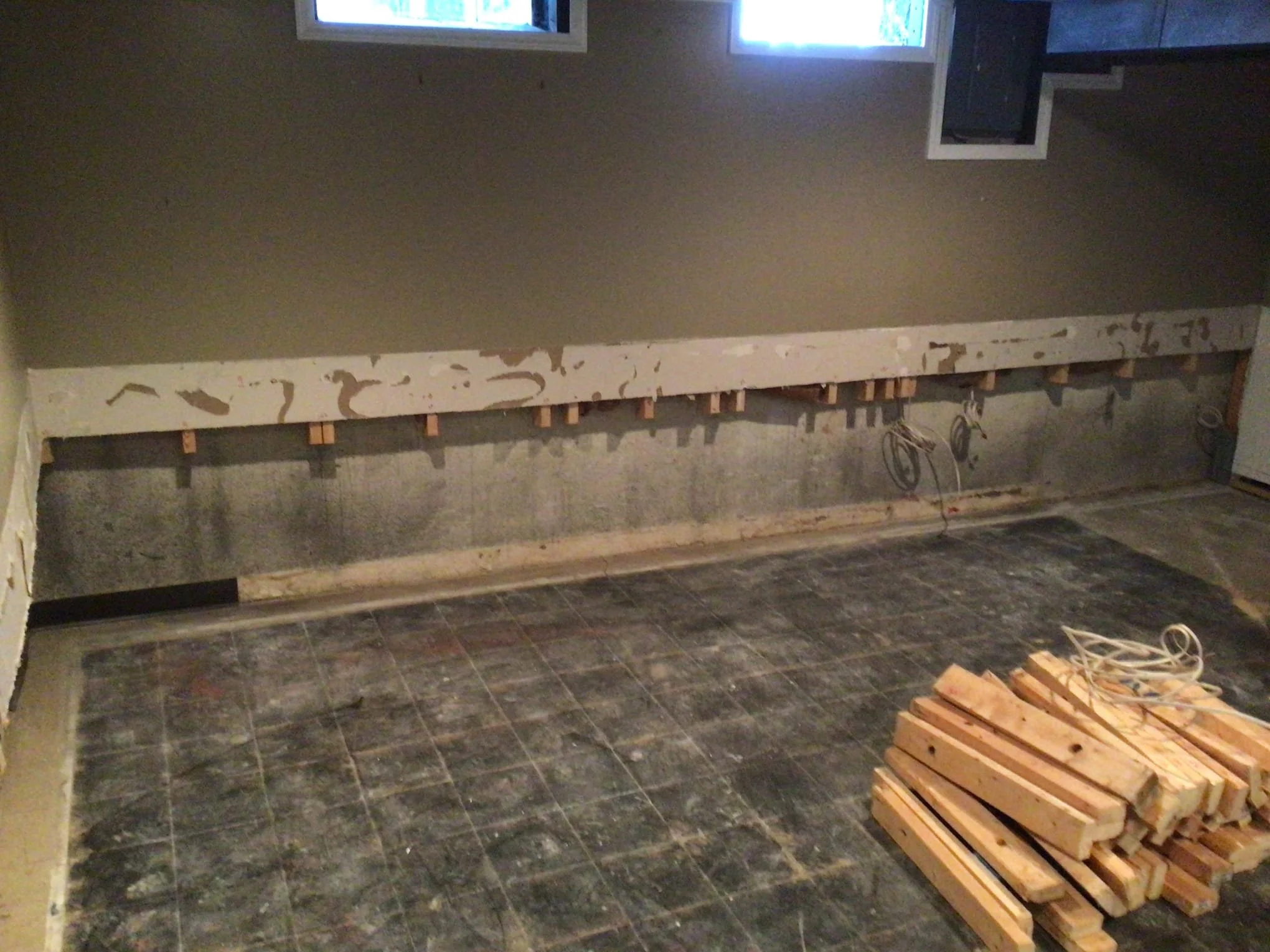 Finished basement in Sterling Heights showing water damage behind walls before waterproofing repairs.
