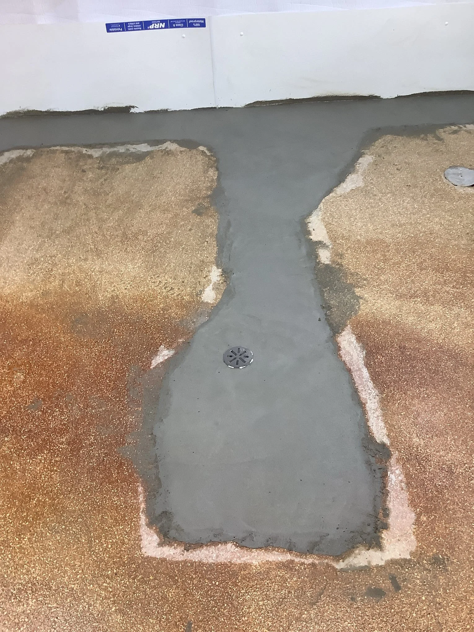 Completed basement waterproofing system in Fraser, Michigan with drain tile, sump pump, and vapor barrier installed.