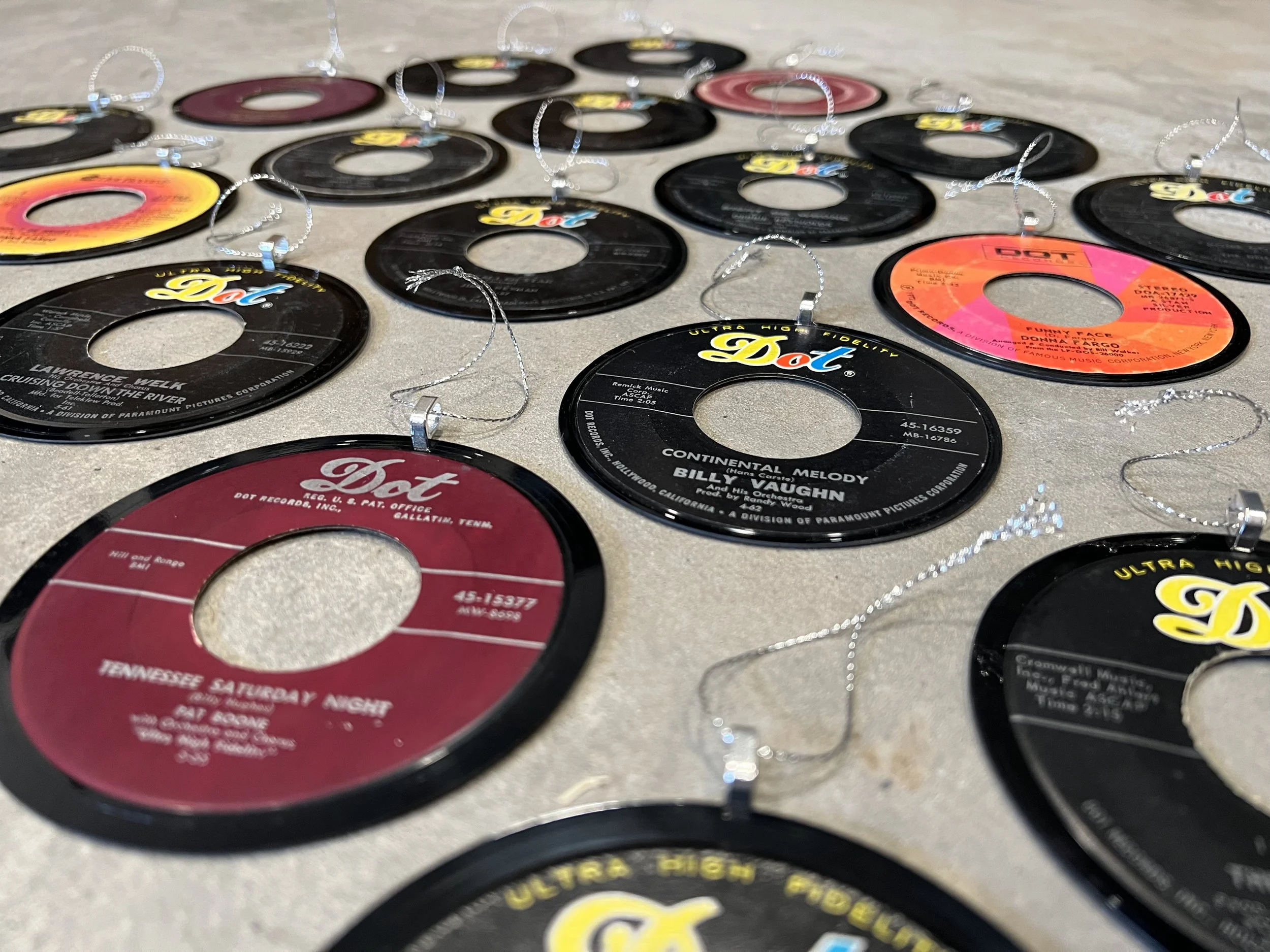 Hollowed vinyl record ornaments on display with chains attached, featuring Dot Records labels, arranged on a flat surface.