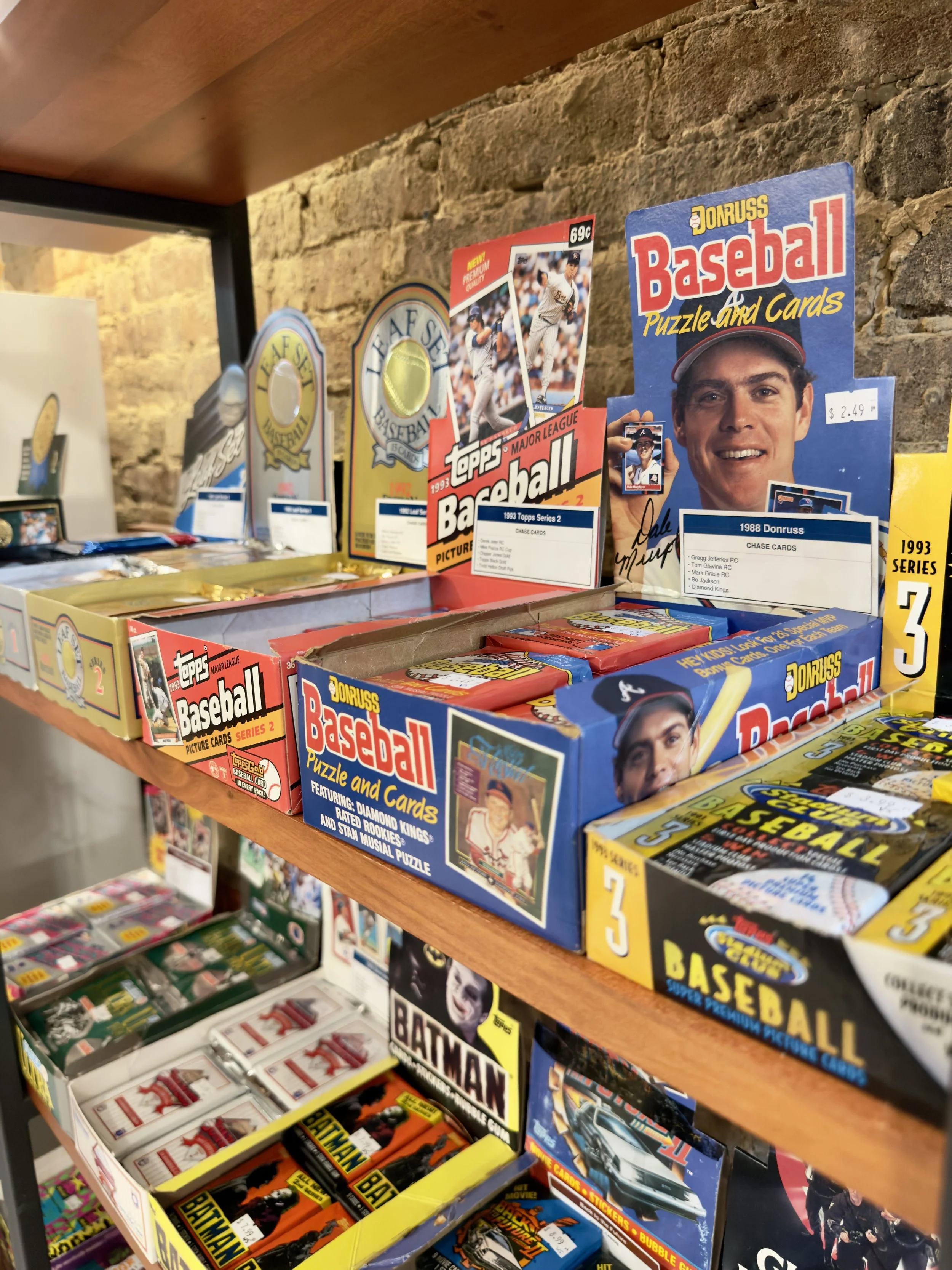 Shelf displaying vintage sport cards - baseball, basketball, football, soccer, collector and others. Card packs in original boxes, including Topps Major League Baseball, Donruss, Fleer, Upper Deck and others.