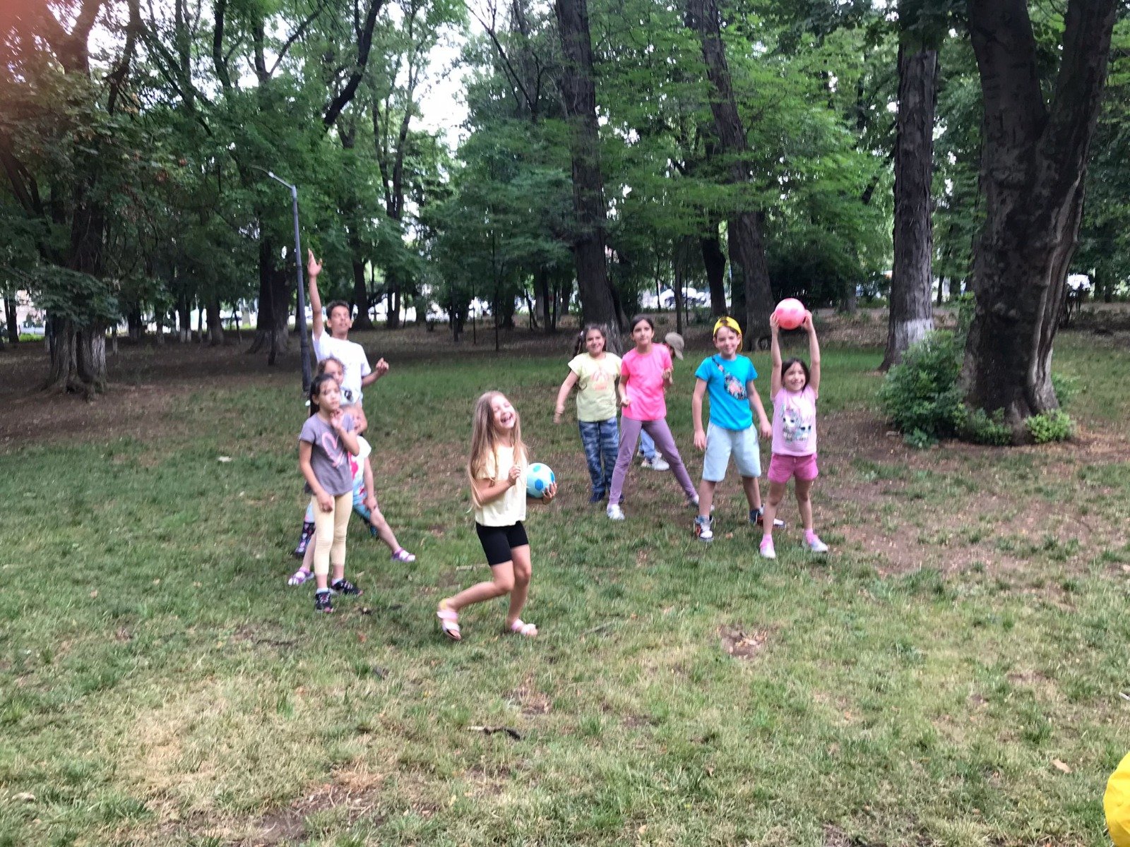 Group of children playing with balls in a park under trees