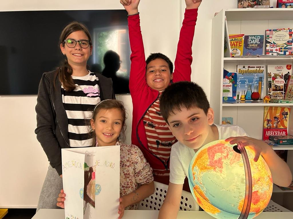 Four children smiling in a room, one holding a globe, another a project labeled "America de Nord." Books are on shelves in the background.