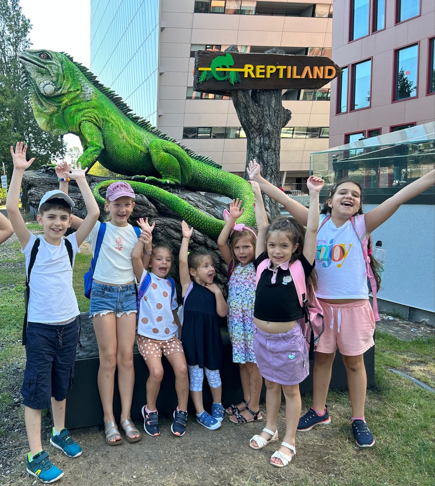 Group of children posing with a large green iguana statue at Reptiland.