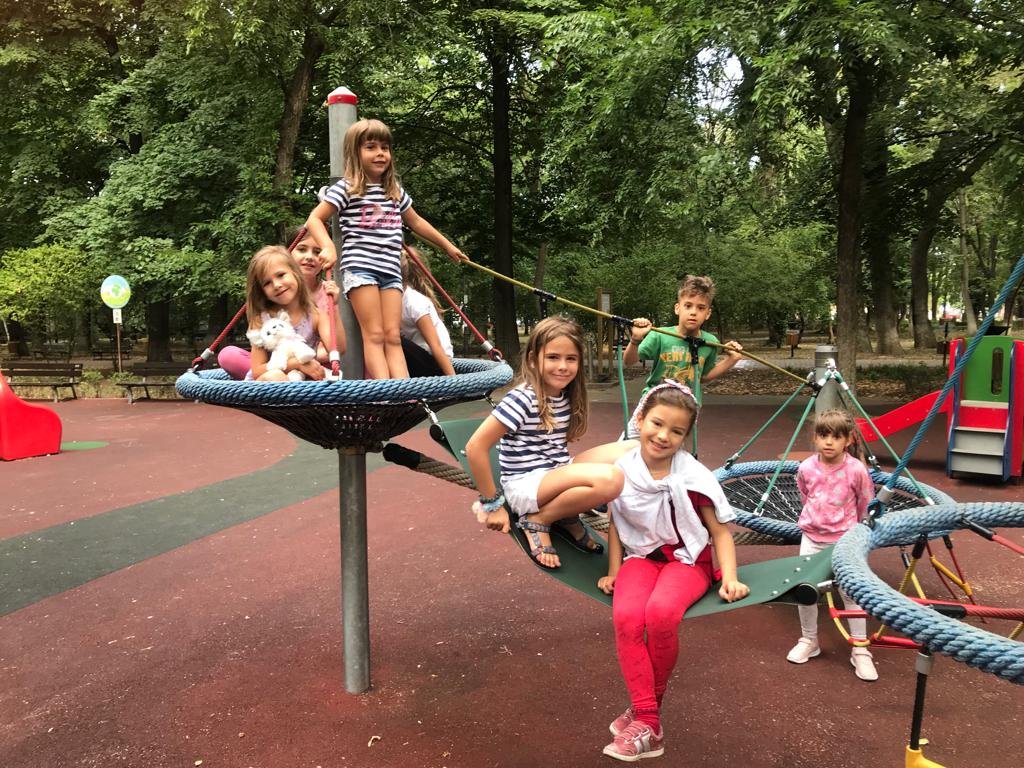 Children playing on climbing equipment at a playground with trees in the background.