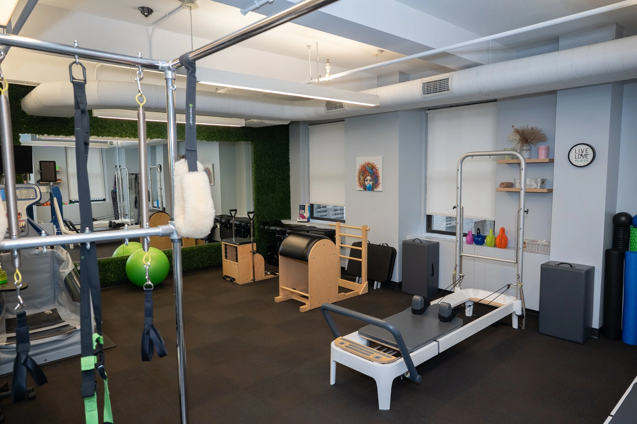Pilates studio with reformer, exercise equipment, and colorful kettlebells